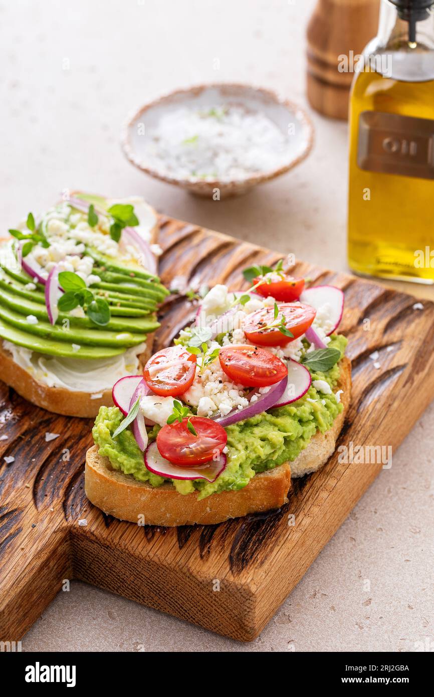 Toasts d'avocat avec radis, tomates et feta garnis d'huile d'olive, idée de petit déjeuner sain Banque D'Images