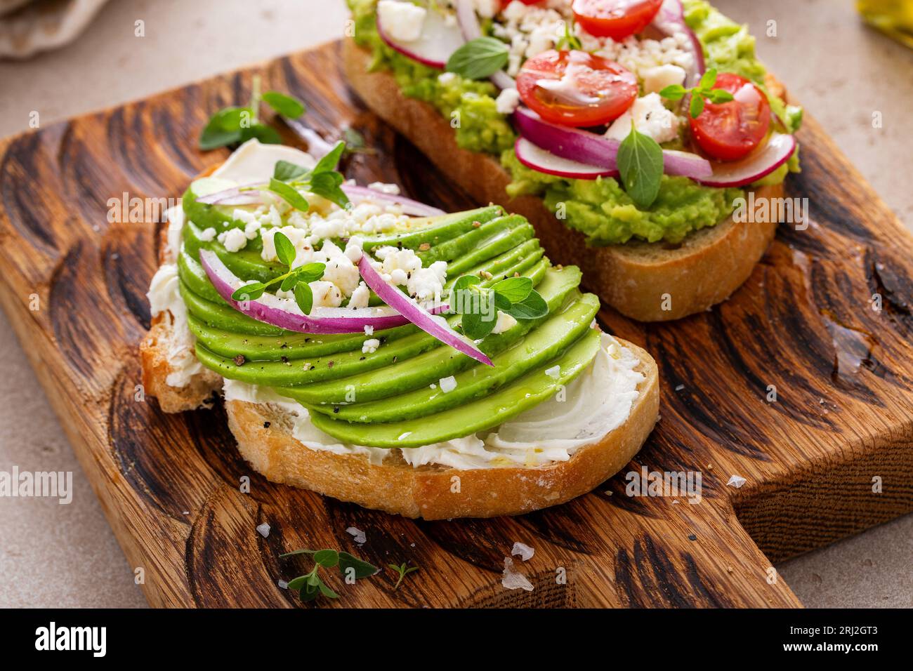 Toasts d'avocat avec radis, tomates et feta garnis d'huile d'olive, idée de petit déjeuner sain Banque D'Images