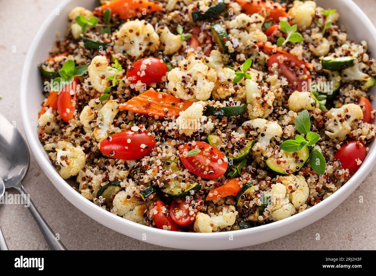 Salade tiède de quinoa avec légumes rôtis et tomates fraîches, idée de plat d'accompagnement sain Banque D'Images