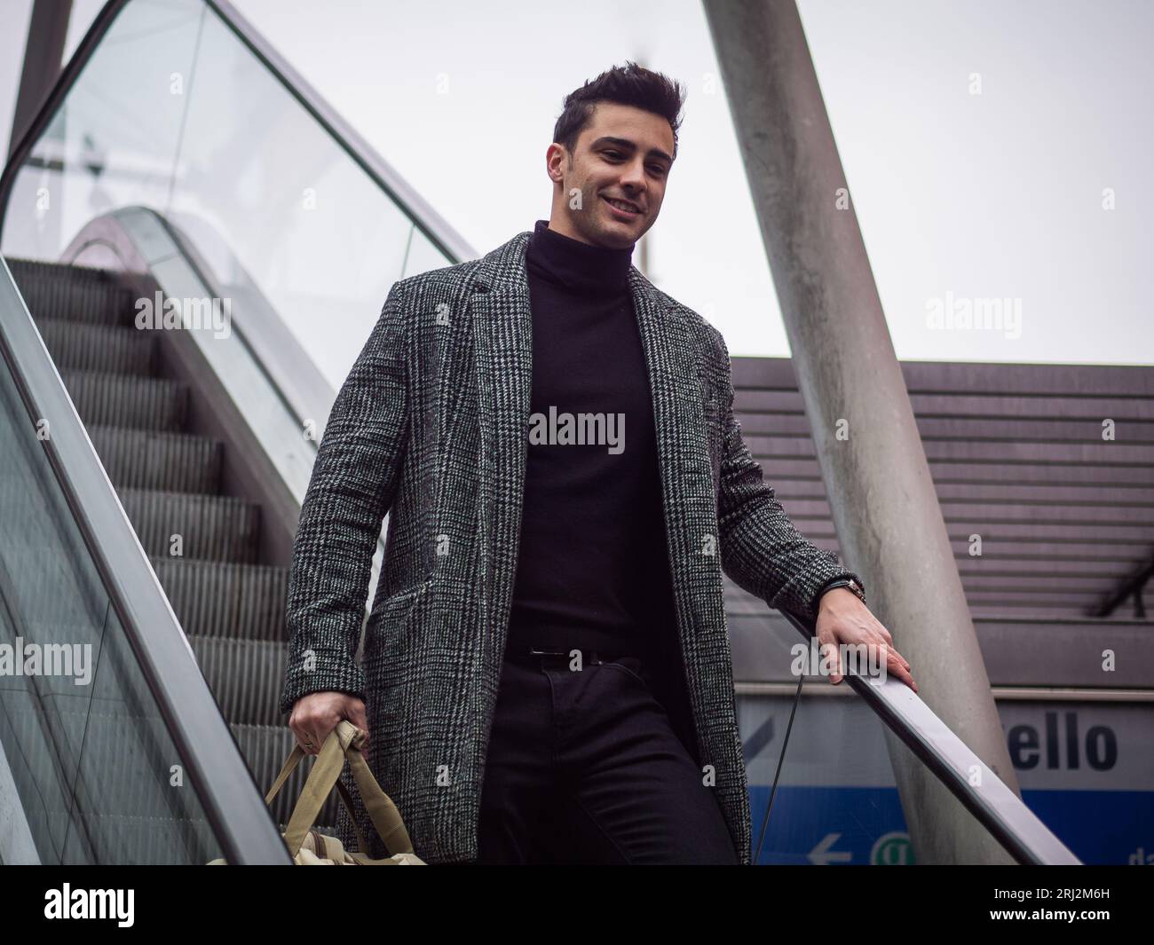 Photo d'un homme debout sur un escalator avec un sac Banque D'Images