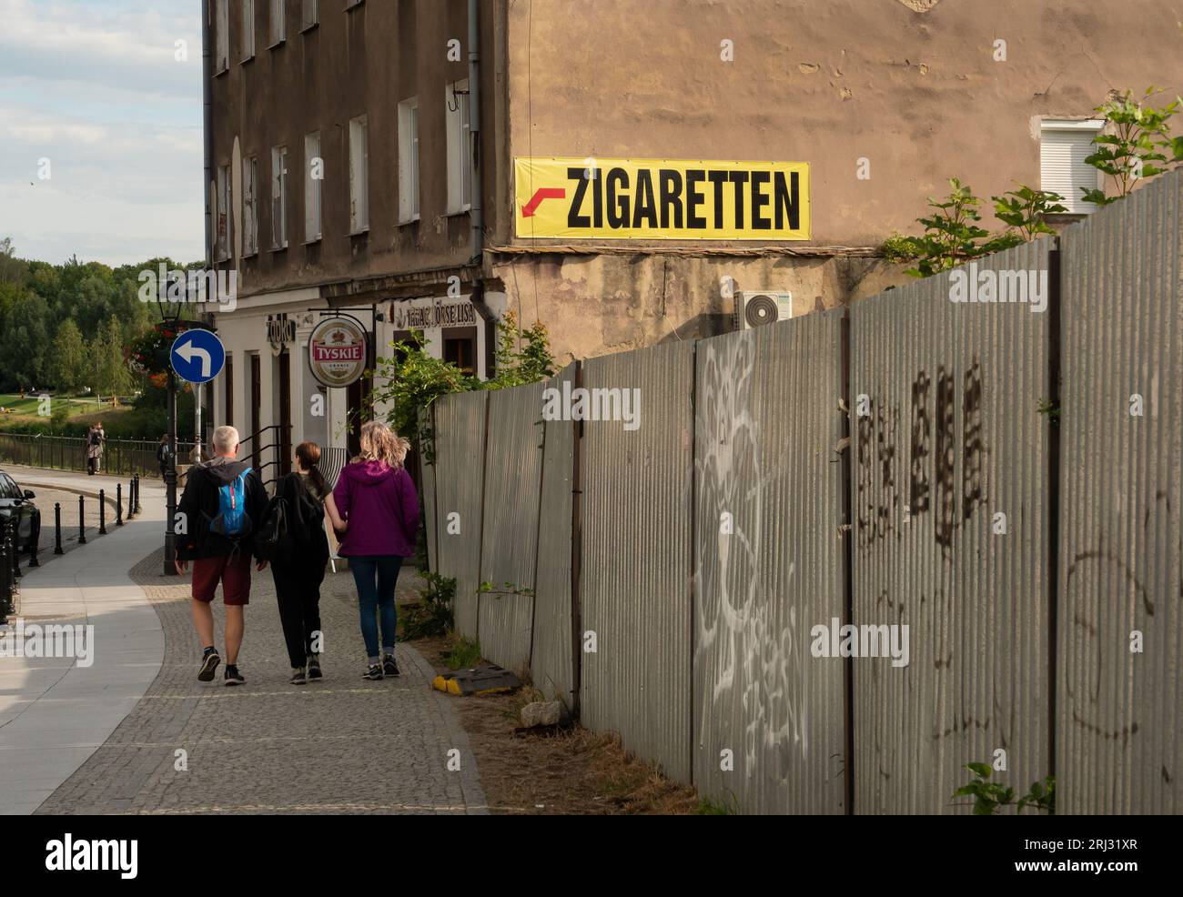 Zgorzelec, Pologne. 08 août 2023. 08.08.2023, Zgorzelec. Un panneau sur un pare-feu annonce l'achat de cigarettes dans un magasin de Zgorzelec, qui est situé à une centaine de mètres derrière la frontière germano-polonaise, un pont de la ville. Les touristes marchent à côté du panneau. Zgorzelec est le voisin polonais de la ville allemande de Goerlitz, sur l'autre rive de la rivière Neisse. Les cigarettes et l'alcool sont moins chers ici qu'en Allemagne. Crédit : Wolfram Steinberg/dpa crédit : Wolfram Steinberg/dpa/Alamy Live News Banque D'Images