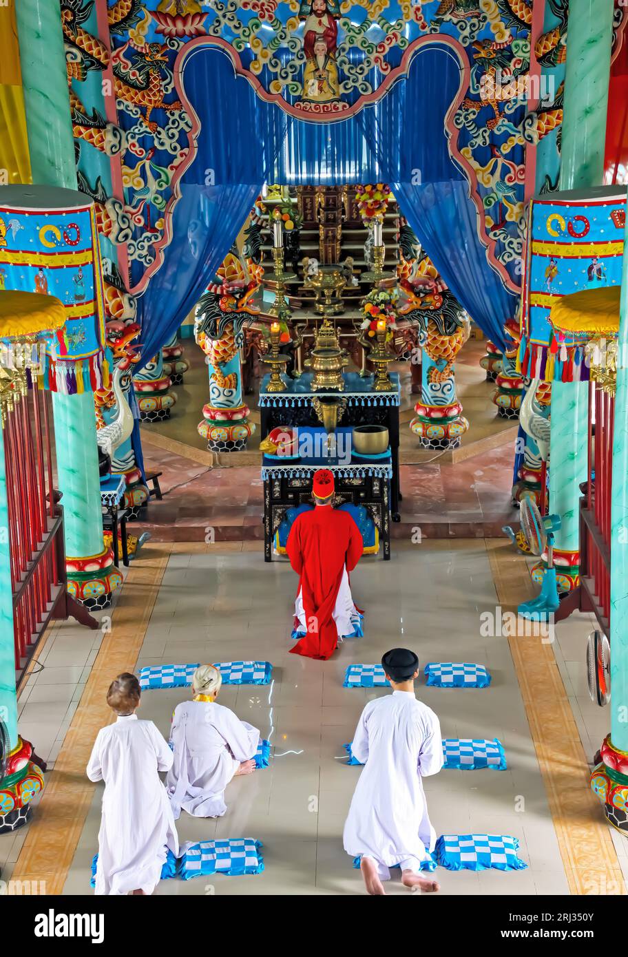 Ho Chi Minh ville, Vietnam - janvier 5. 2015 : salle intérieure de l'église CAO Dai (Caodaïsme) avec prêtre et croyants en robes blanches, autel coloré Banque D'Images