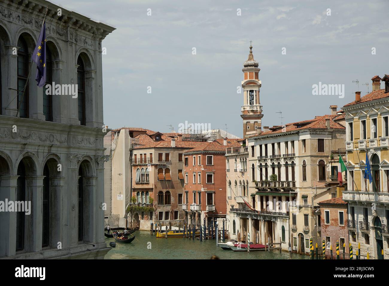 Une vue sur une rivière à Venise, en Italie, avec plusieurs bateaux de différentes tailles et couleurs, naviguant le long de l'eau calme et bleue Banque D'Images