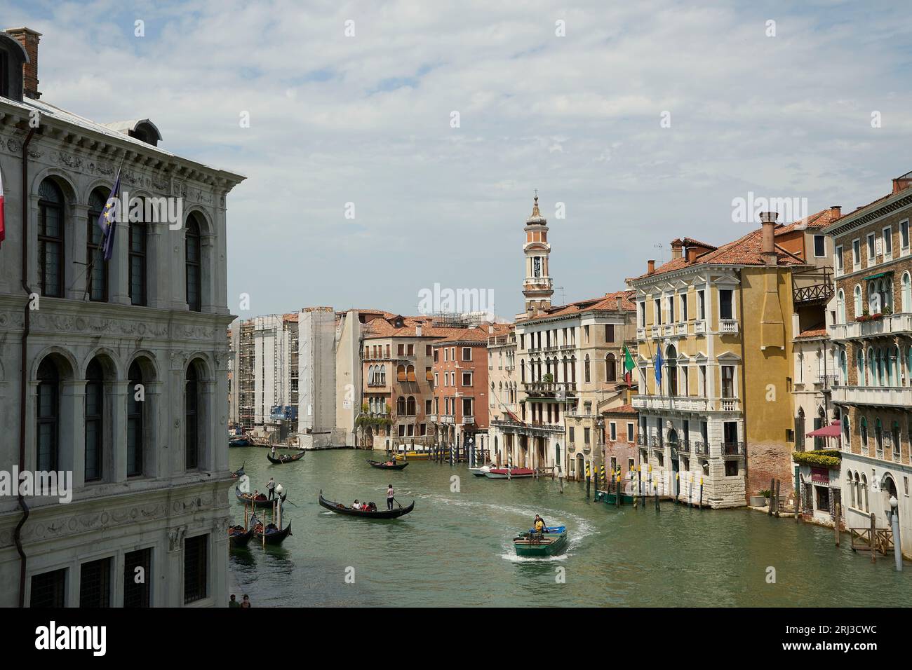 Une vue sur une rivière à Venise, en Italie, avec plusieurs bateaux de différentes tailles et couleurs, naviguant le long de l'eau calme et bleue Banque D'Images