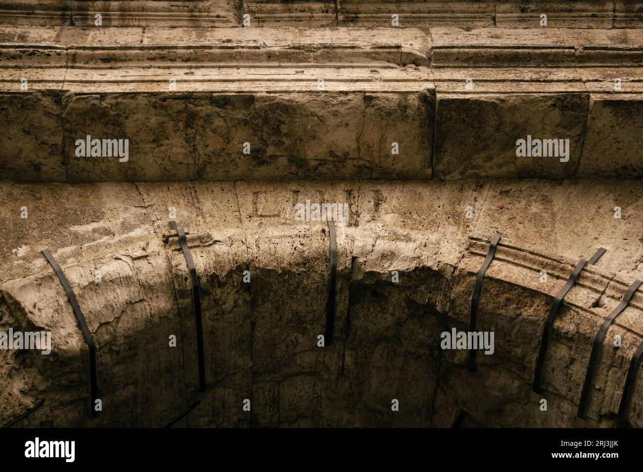 Gros plan d'un mur de pierre patiné du Colisée à Rome, en Italie, avec une ancienne inscription au premier plan Banque D'Images
