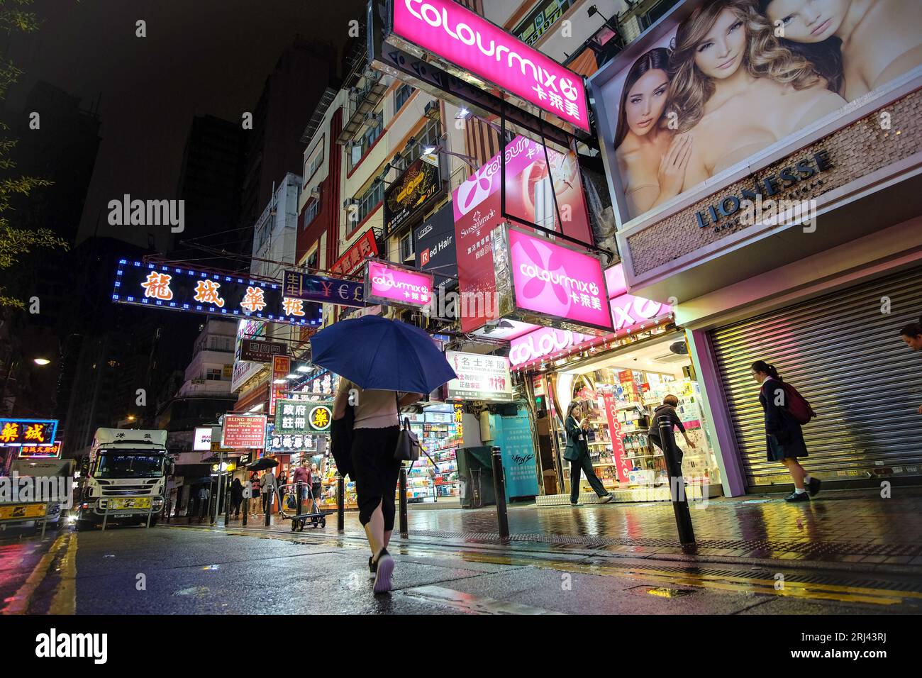 Piétons et acheteurs se déplacent dans les rues de Hong Kong dans une averse de pluie Banque D'Images