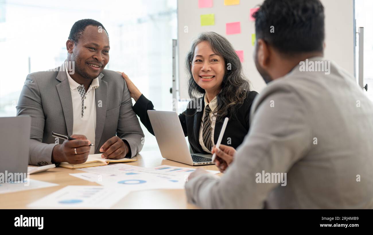 Une femme d'affaires asiatique senior heureuse est en réunion avec des hommes d'affaires afro-américains. conseil, séminaire, collègues divers, collaboration, affaires Banque D'Images