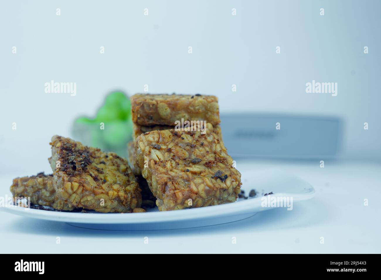 Une photo en gros plan de tempeh frit, soigneusement empilé, présenté sur une assiette blanche. Photo de nourriture isolée. Banque D'Images