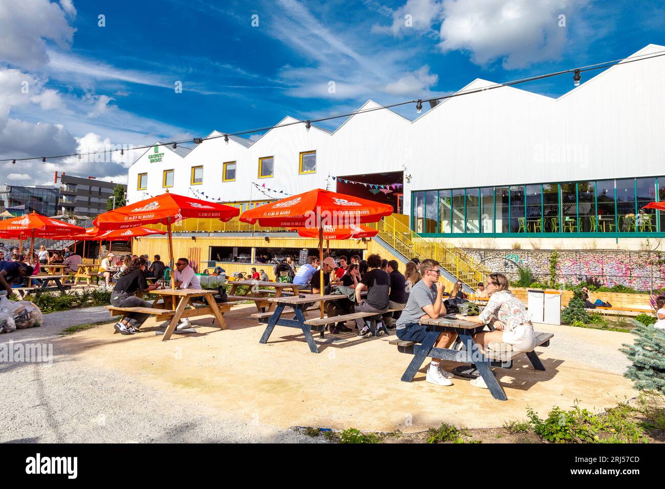 Personnes assises à l'extérieur à l'espace de co-working de Hackney Bridge, au complexe de vente au détail et au marché de la nourriture de rue, Hackney, Londres, Royaume-Uni Banque D'Images