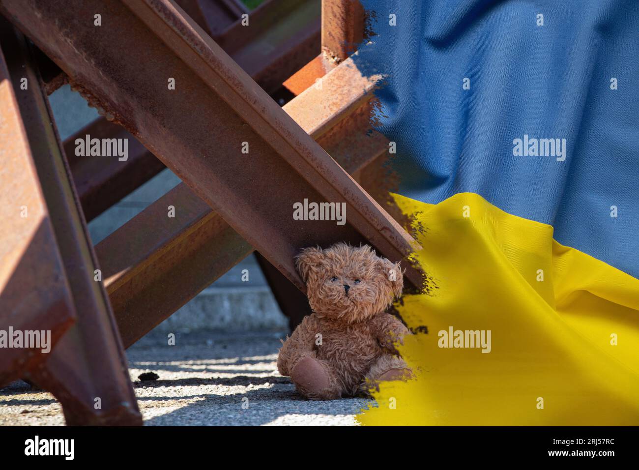Un ours en peluche se trouve à côté d'un hérisson anti-char sur fond du drapeau de l'Ukraine, la guerre en Ukraine Banque D'Images