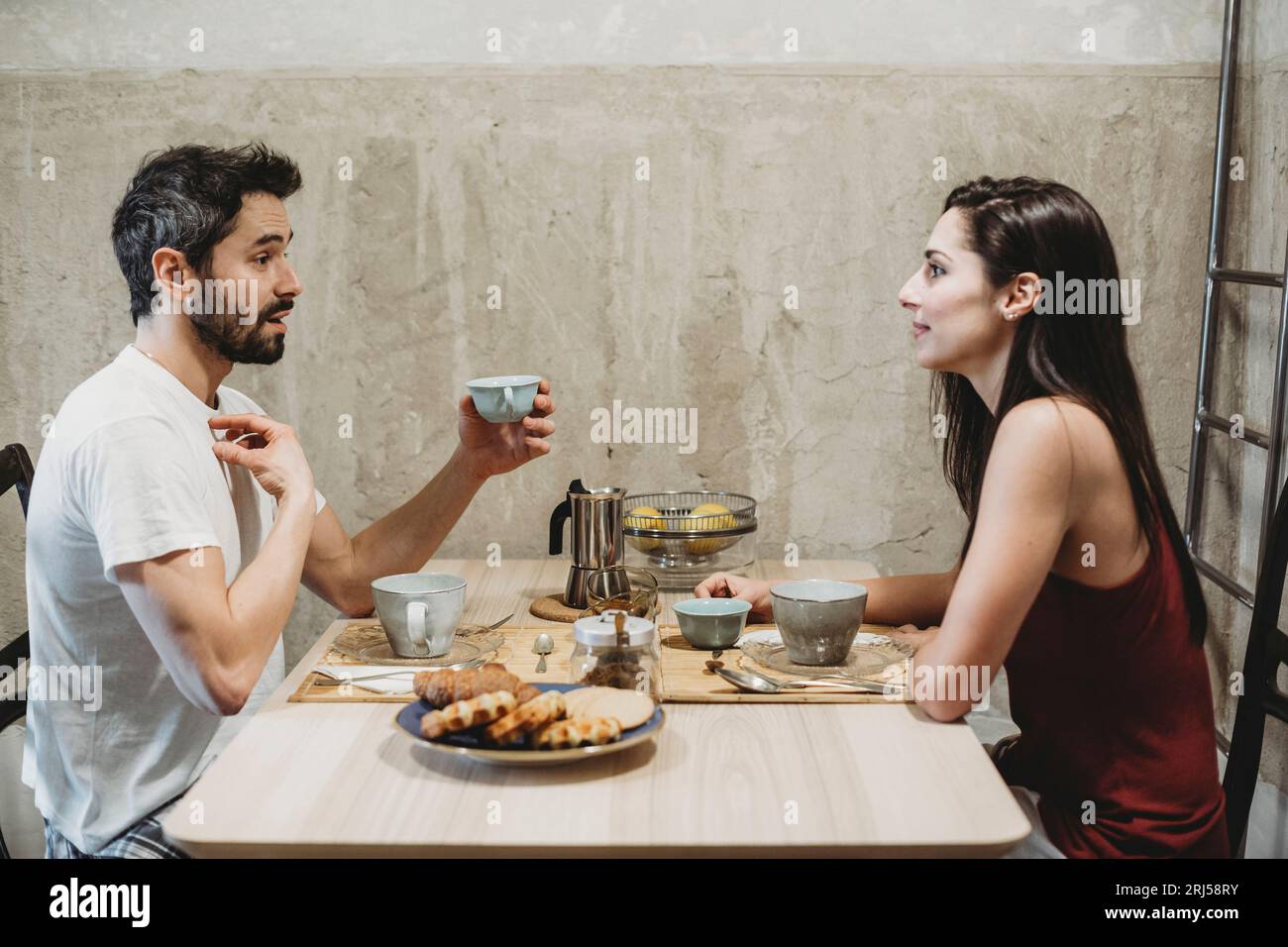 Jeune couple heureux en amour prenant le petit déjeuner à la table de la cuisine Banque D'Images