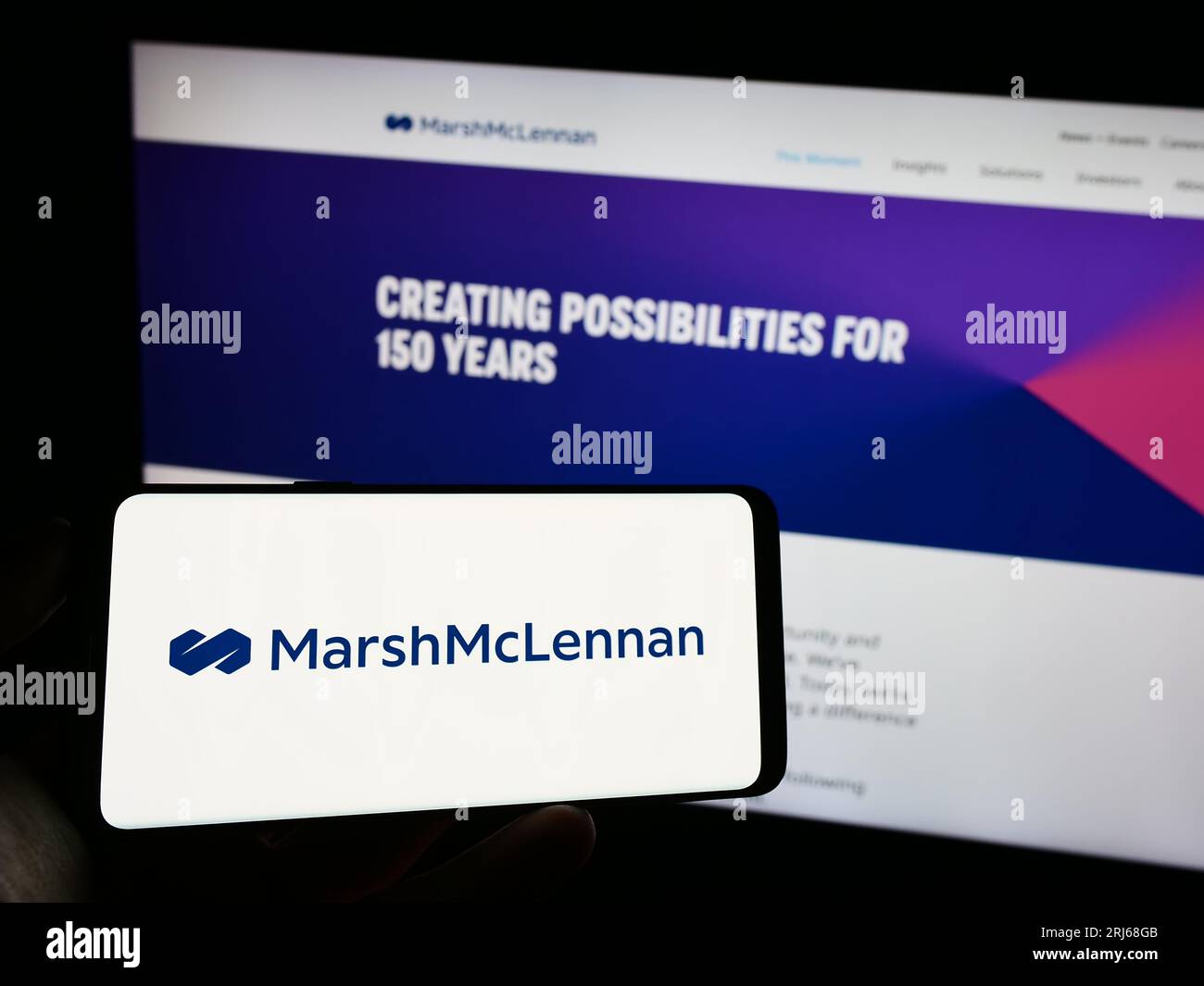 Personne détenant un téléphone cellulaire avec le logo de la société américaine Marsh McLennan Companies Inc. À l'écran devant la page Web de l'entreprise. Concentrez-vous sur l'affichage du téléphone. Banque D'Images