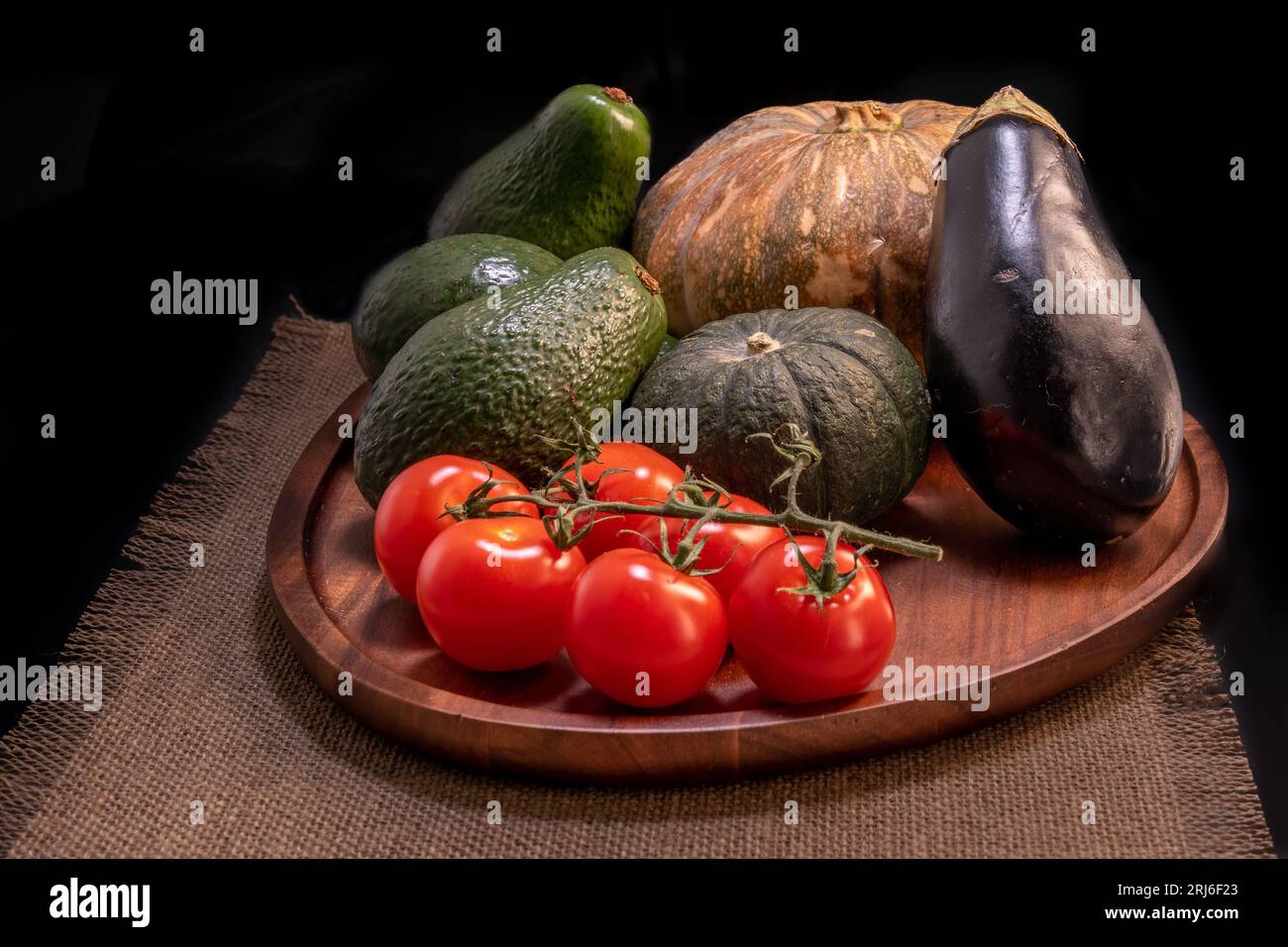 Une planche en bois avec des légumes et des produits - tomates, avocats, aubergines et citrouilles Banque D'Images