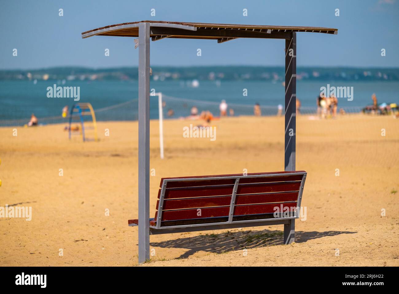 Banc avec un auvent sur la plage sur un fond flou avec des gens se baignant Banque D'Images