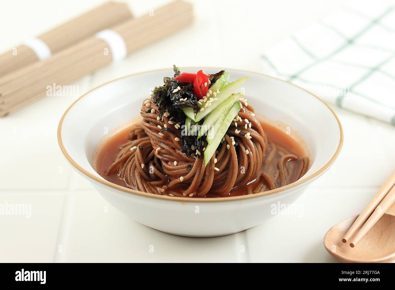 Bibim Naengmyeon nouilles Soba, soupe froide au sarrasin ou Guksu, nouilles épicées coréennes avec Gochujang. Sur la table blanche Banque D'Images