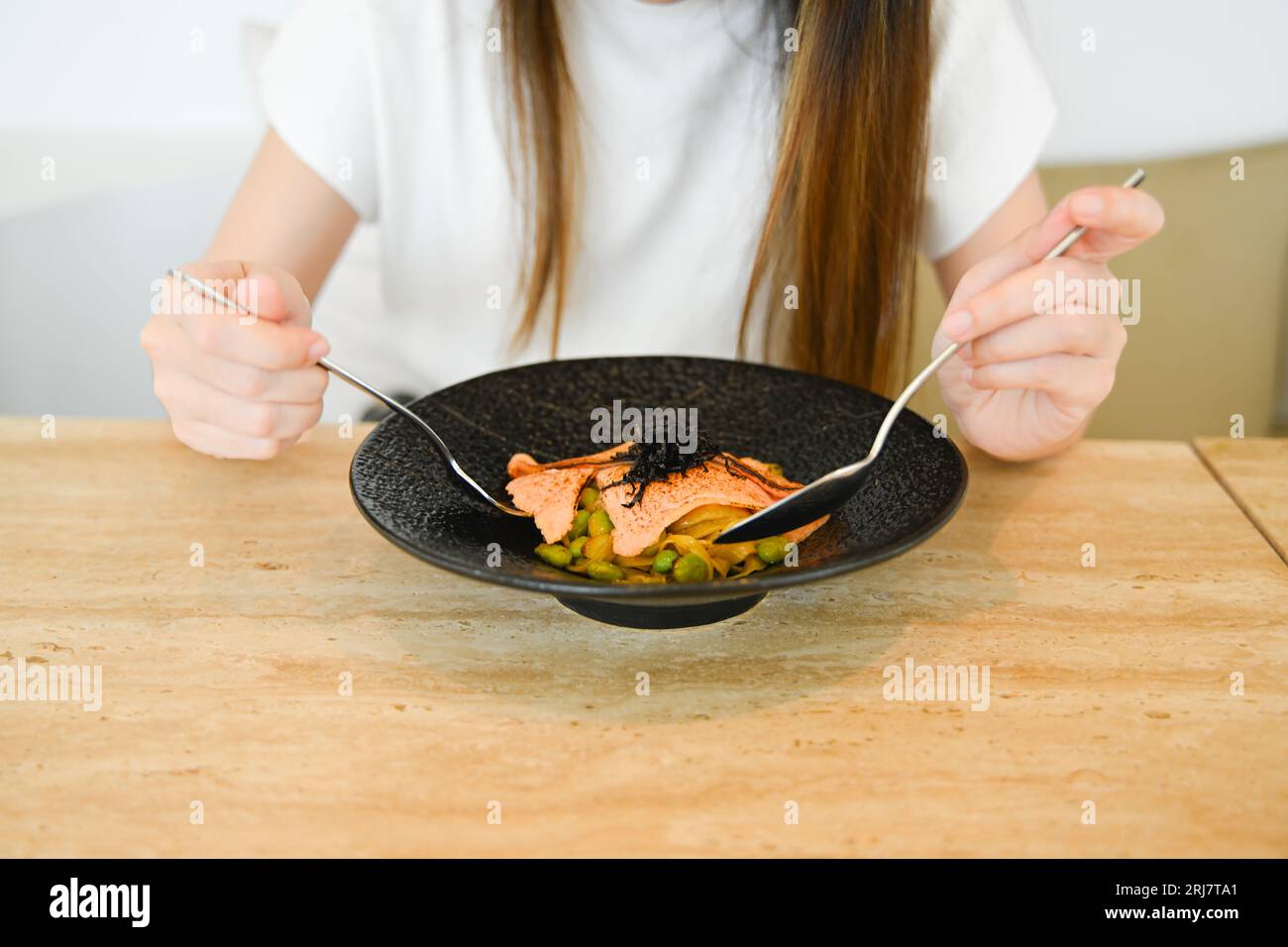 photo d'une femme aime manger beaucoup, tenir une assiette de nourriture, sourire à la caméra, et profiter de son repas sans se soucier d'être en surpoids ou Banque D'Images