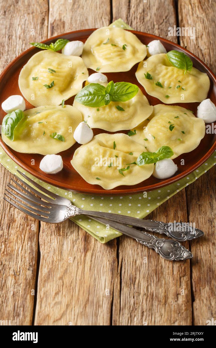 Pâtes italiennes Cappellacci mozzarella au basilic closeup sur l'assiette sur la table en bois. Vertical Banque D'Images