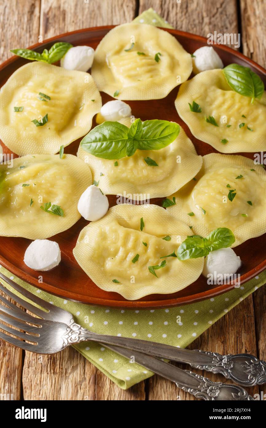 Ravioli Cappellacci boulettes avec mozzarella et herbes closeup sur l'assiette sur la table en bois. Vertical Banque D'Images