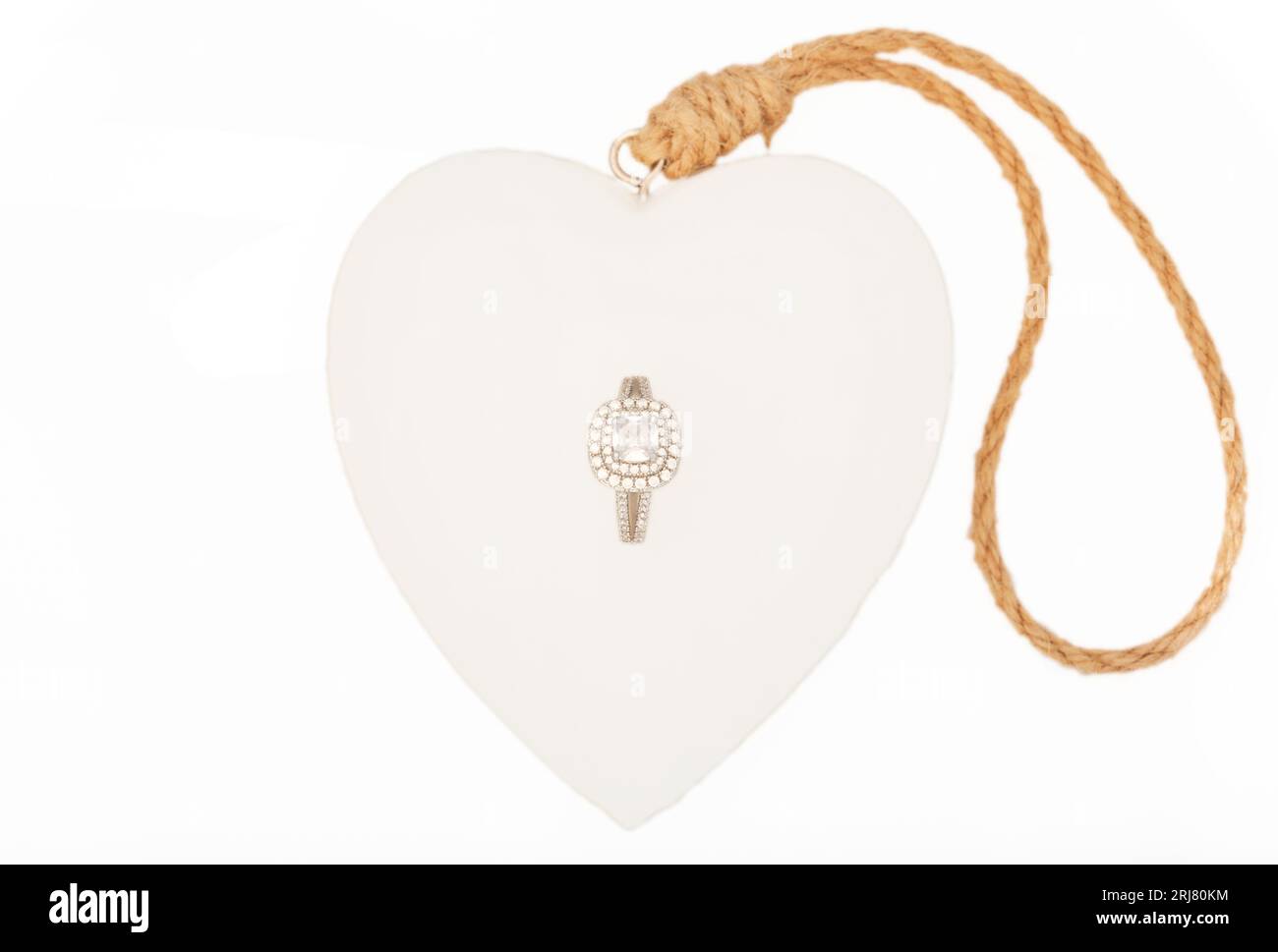 Bague élégante pour dames avec des pierres étincelantes serties sur un cœur d'amour avec un fond blanc. Banque D'Images