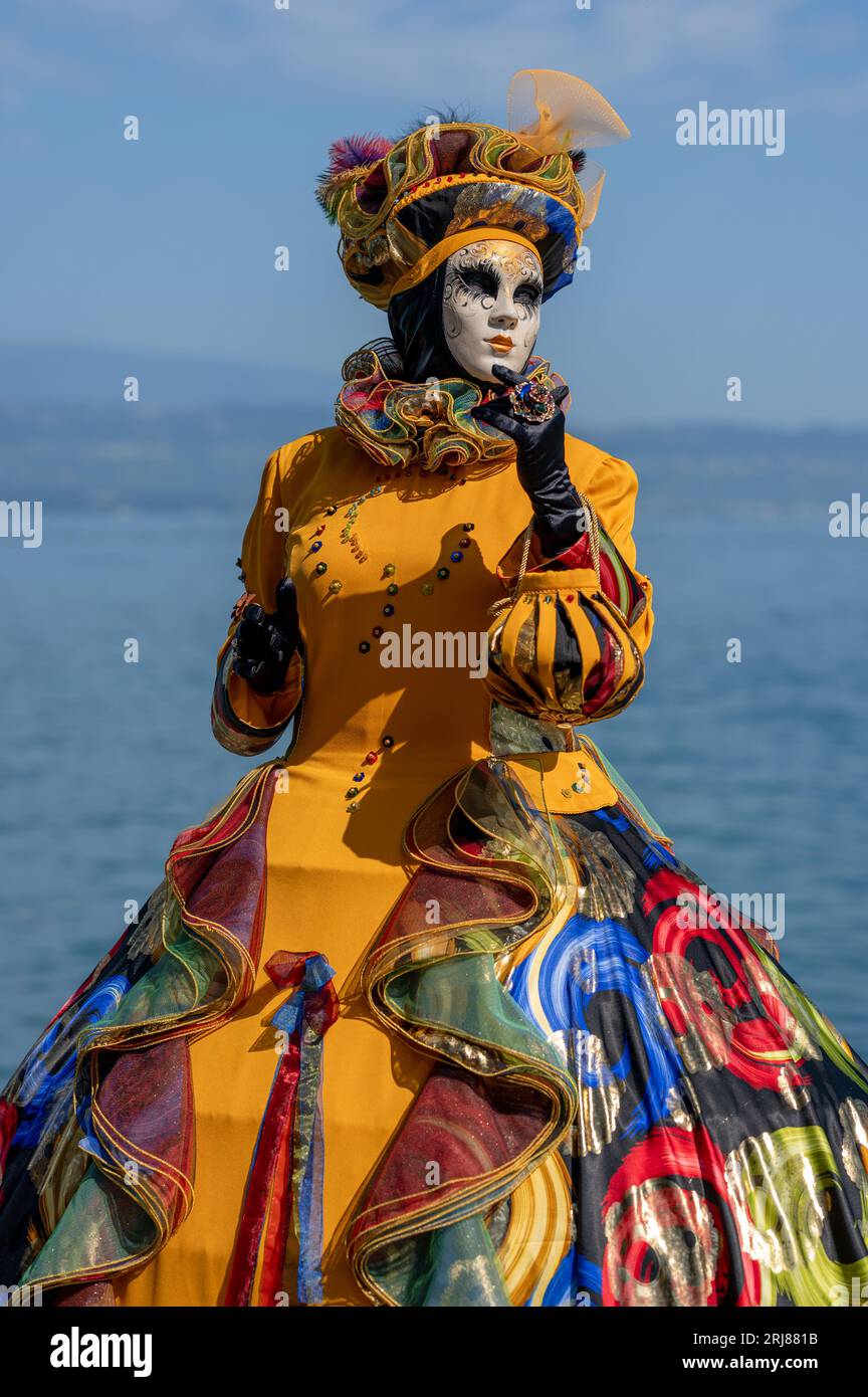 Carnaval vénitien. Une femme portant des costumes de carnaval orange et un masque vénitien. Yvoire, France. Banque D'Images