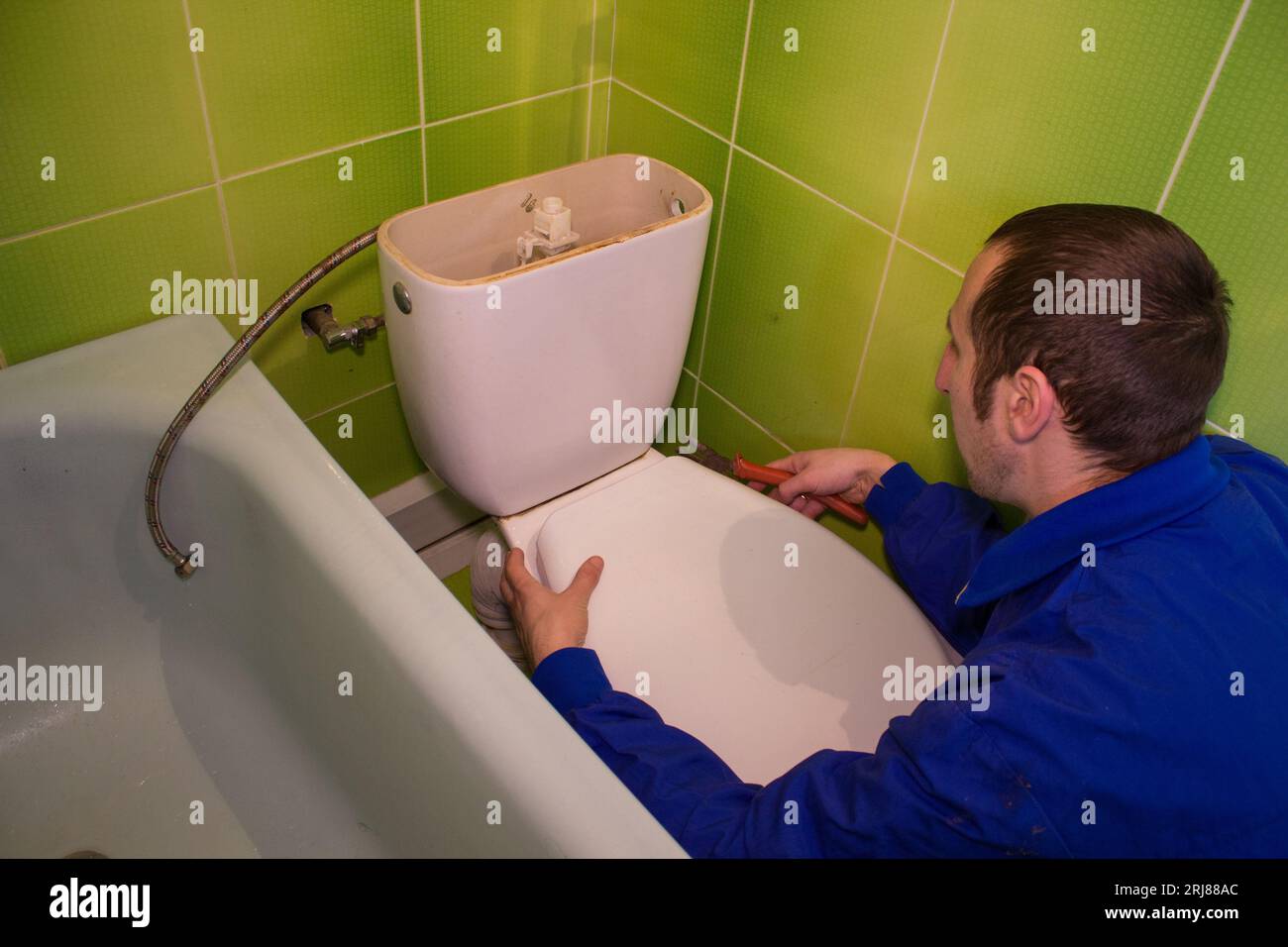 l'homme dévisse un réservoir de vidange d'une toilette Banque D'Images