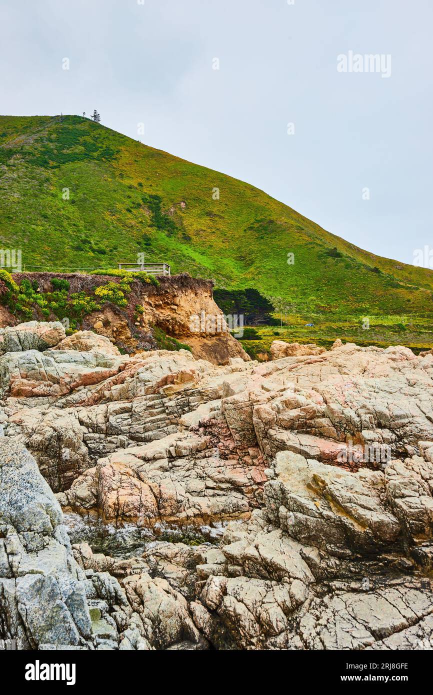 Face de falaise rocheuse de Baren avec des rochers dentelés et une colline montagneuse verte lointaine sous un ciel couvert Banque D'Images
