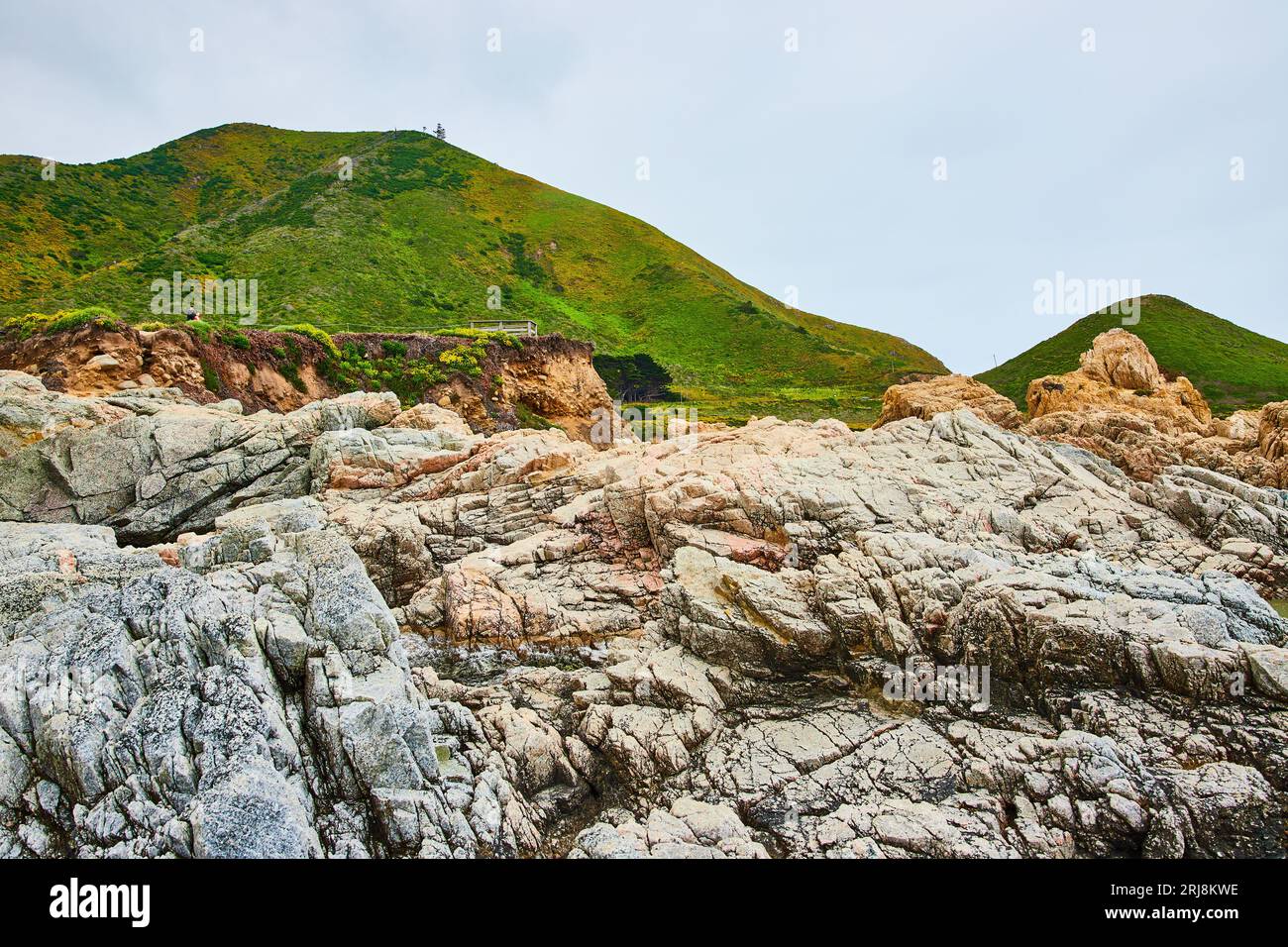 La falaise rocheuse de Baren se dresse dans des rochers déchiquetés avec une colline montagneuse verte lointaine et un ciel couvert Banque D'Images