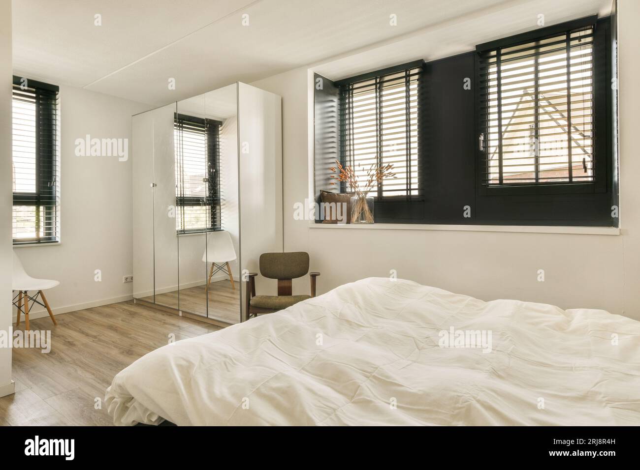 une chambre avec parquet et draps blancs sur le lit, volets ouverts pour laisser entrer la lumière naturelle Banque D'Images
