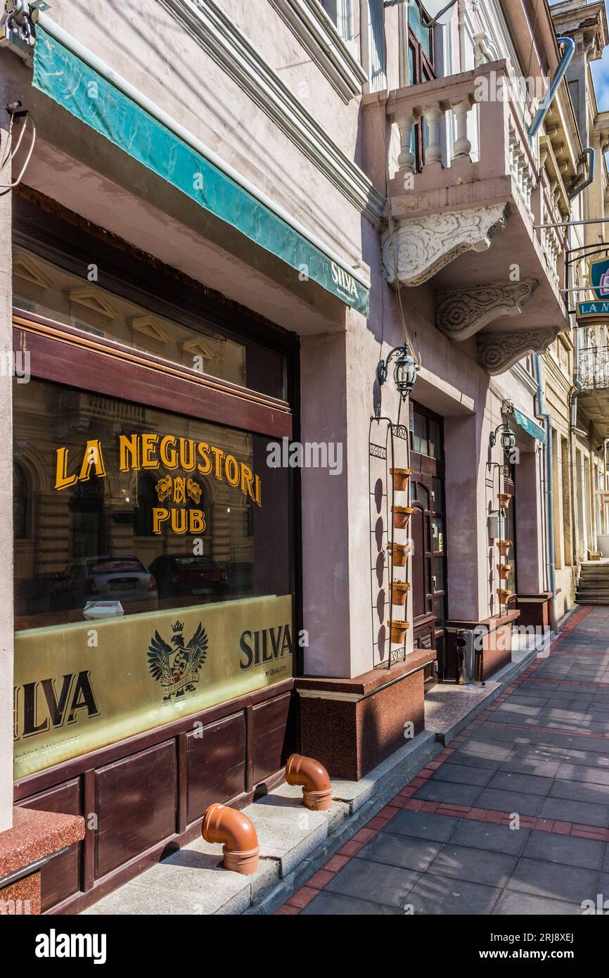 Une vue extérieure d'un mur blanc avec un panneau noir et jaune indiquant « la Negustori Pub » affiché sur le côté d'un bâtiment Banque D'Images