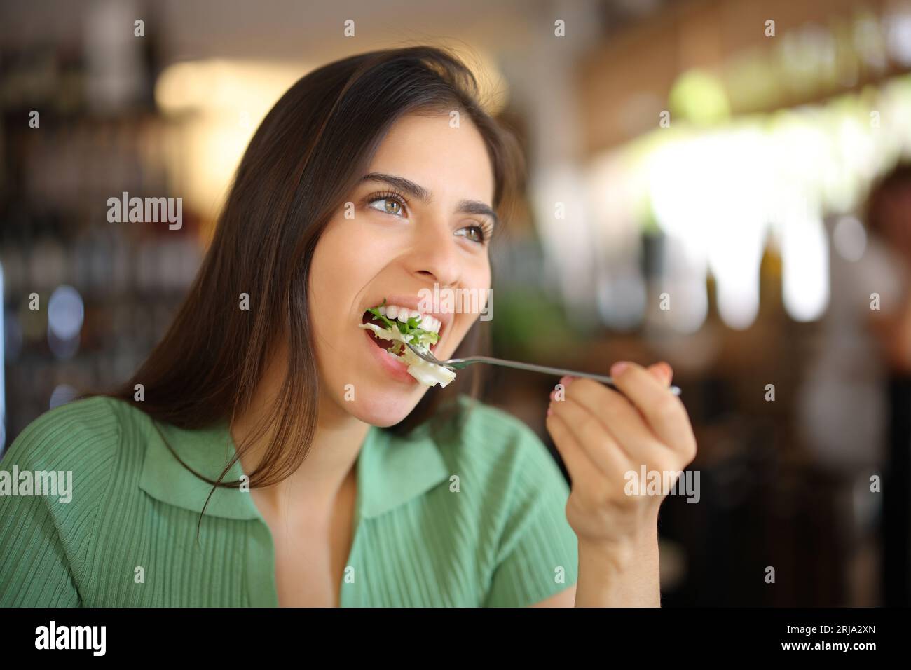 Femme mangeant de la laitue dans un restaurant regardant loin Banque D'Images