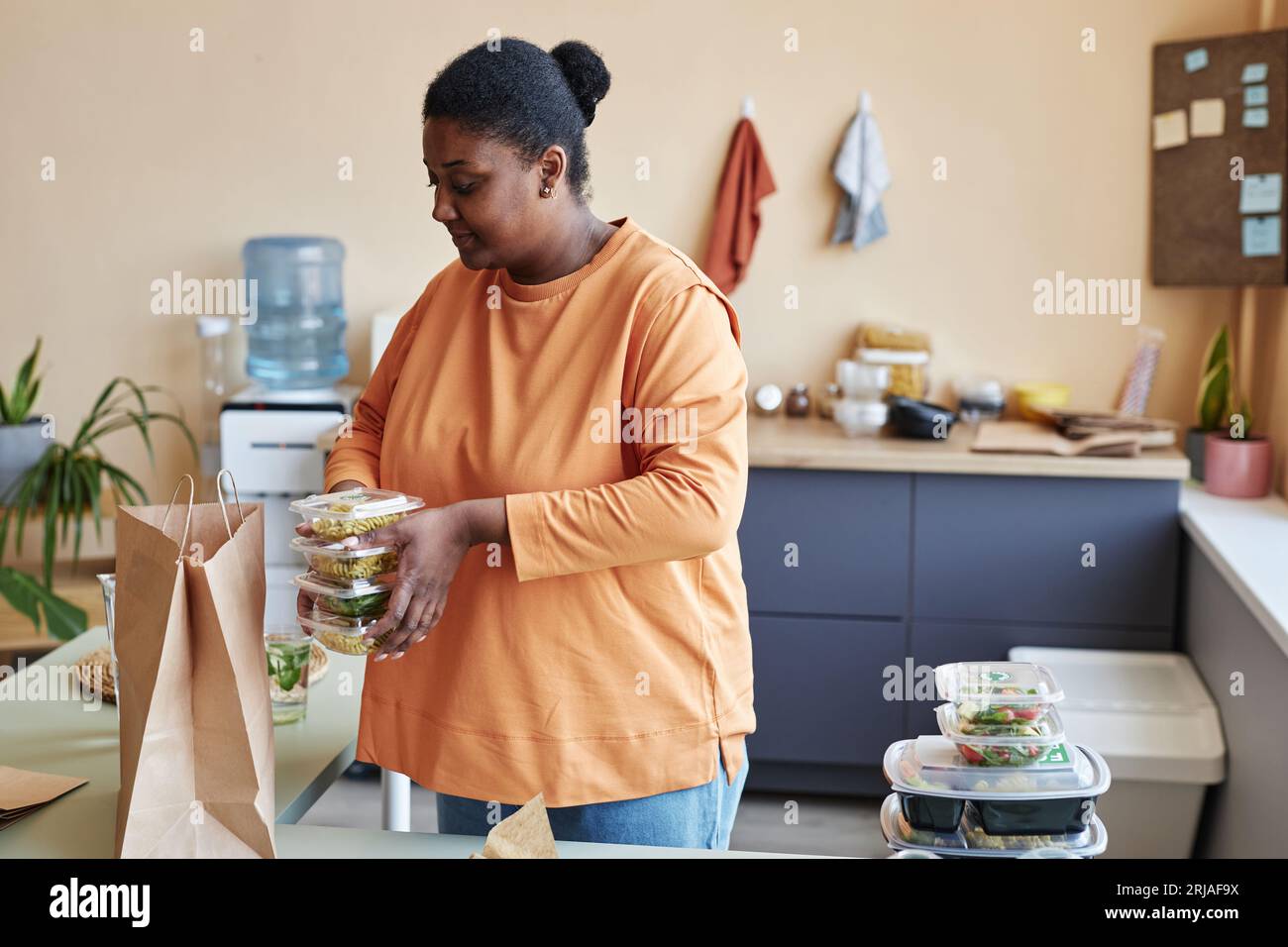 Portrait de femme noire déballant le sac de livraison de nourriture dans la cuisine et souriant, espace de copie Banque D'Images