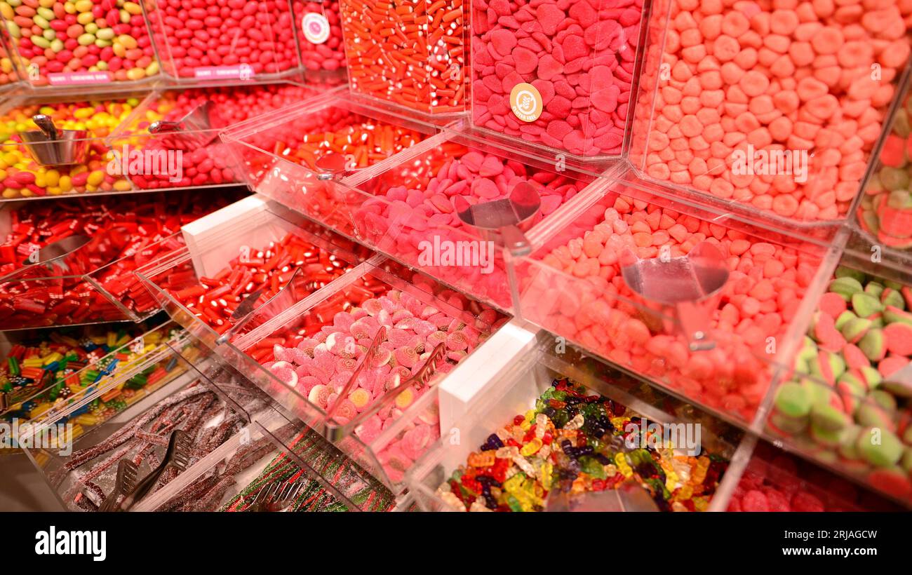 Bocaux en plastique remplis de bonbons colorés dans la boutique. Banque D'Images