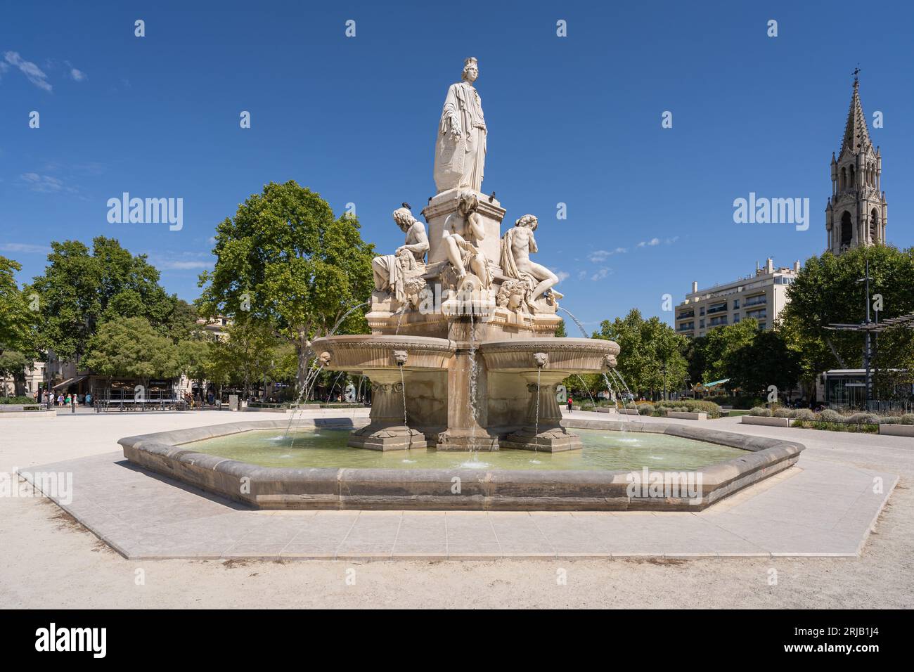 Nîmes, Gard, France - 08 17 2023 : vue d'été de la fontaine Pradier sur l'esplanade Charles de Gaulle, avec l'église St Perpetue en arrière-plan Banque D'Images