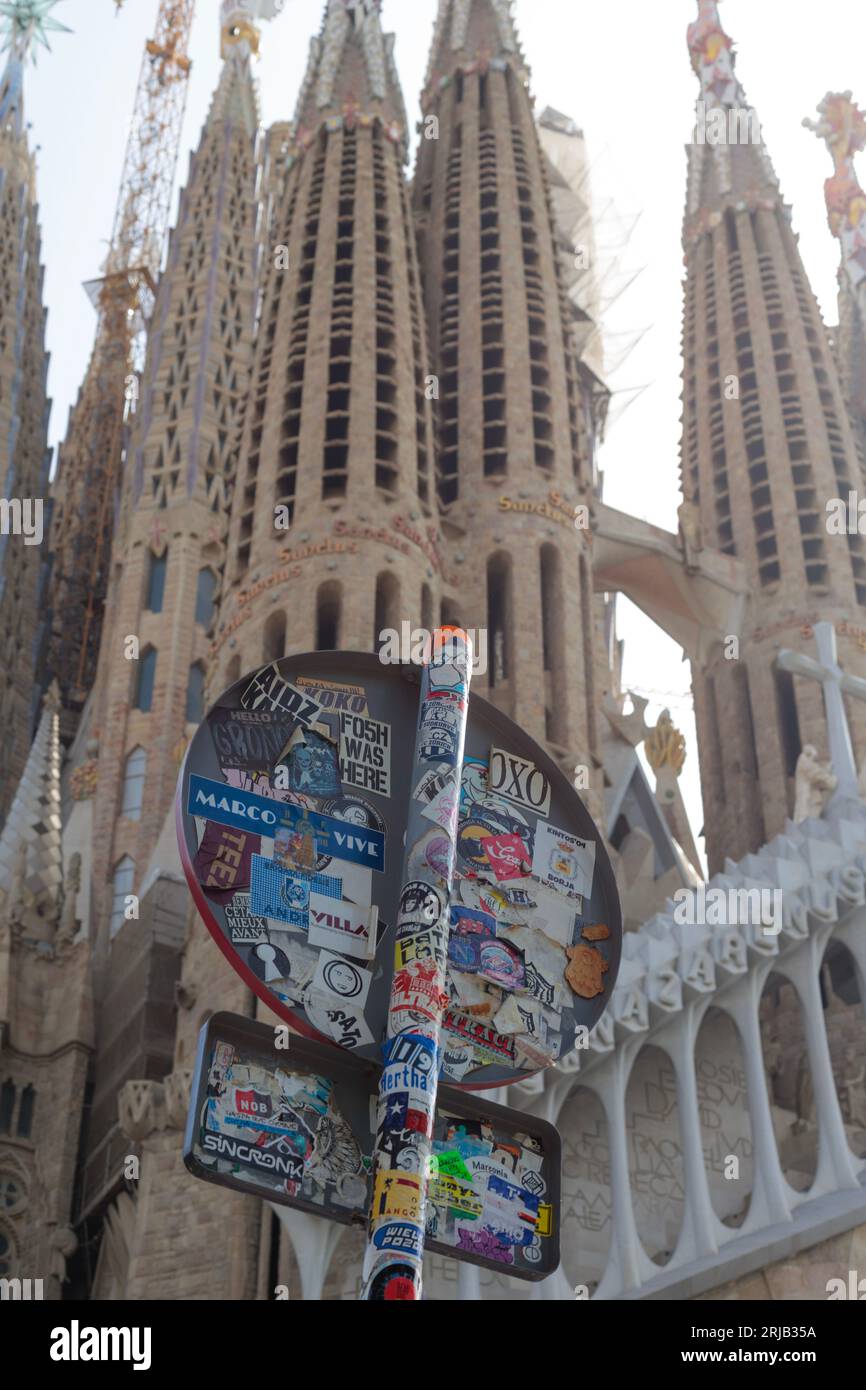 Un panneau routier à Barcelone, recouvert d'autocollants, indiquant un lieu touristique populaire près de la Sagrada Familia. Banque D'Images