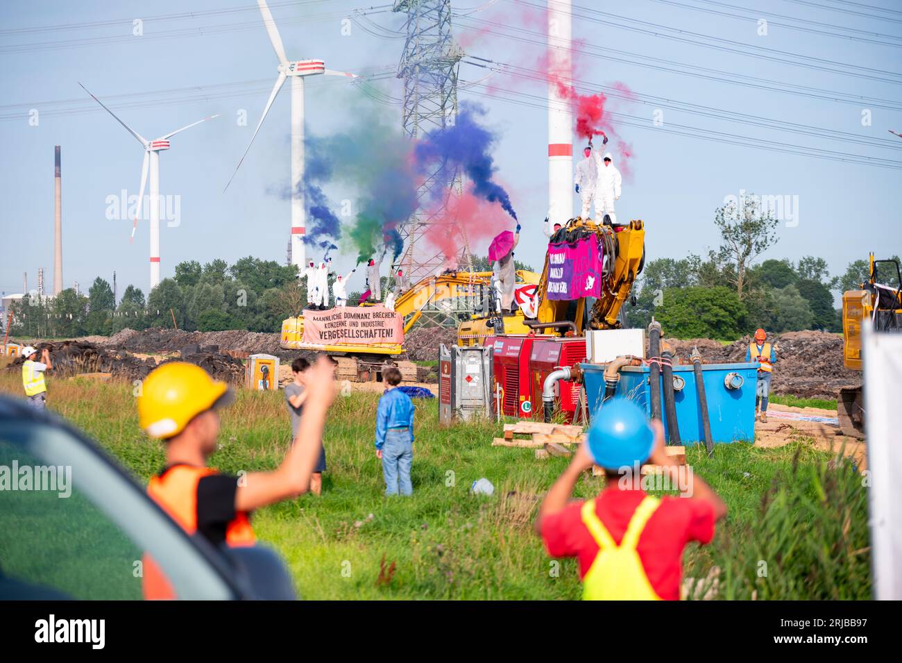 22 août 2023, Schleswig-Holstein, Brunsbüttel : des militants du groupe 'Ende Gelände' brandissent des banderoles sur l'excavatrice d'un chantier de construction et enflamment des fusées éclairantes. Depuis le matin, des militants occupent un chantier de construction où des tuyaux pour un gazoduc de GNL doivent être posés. Photo : Jonas Walzberg/dpa Banque D'Images