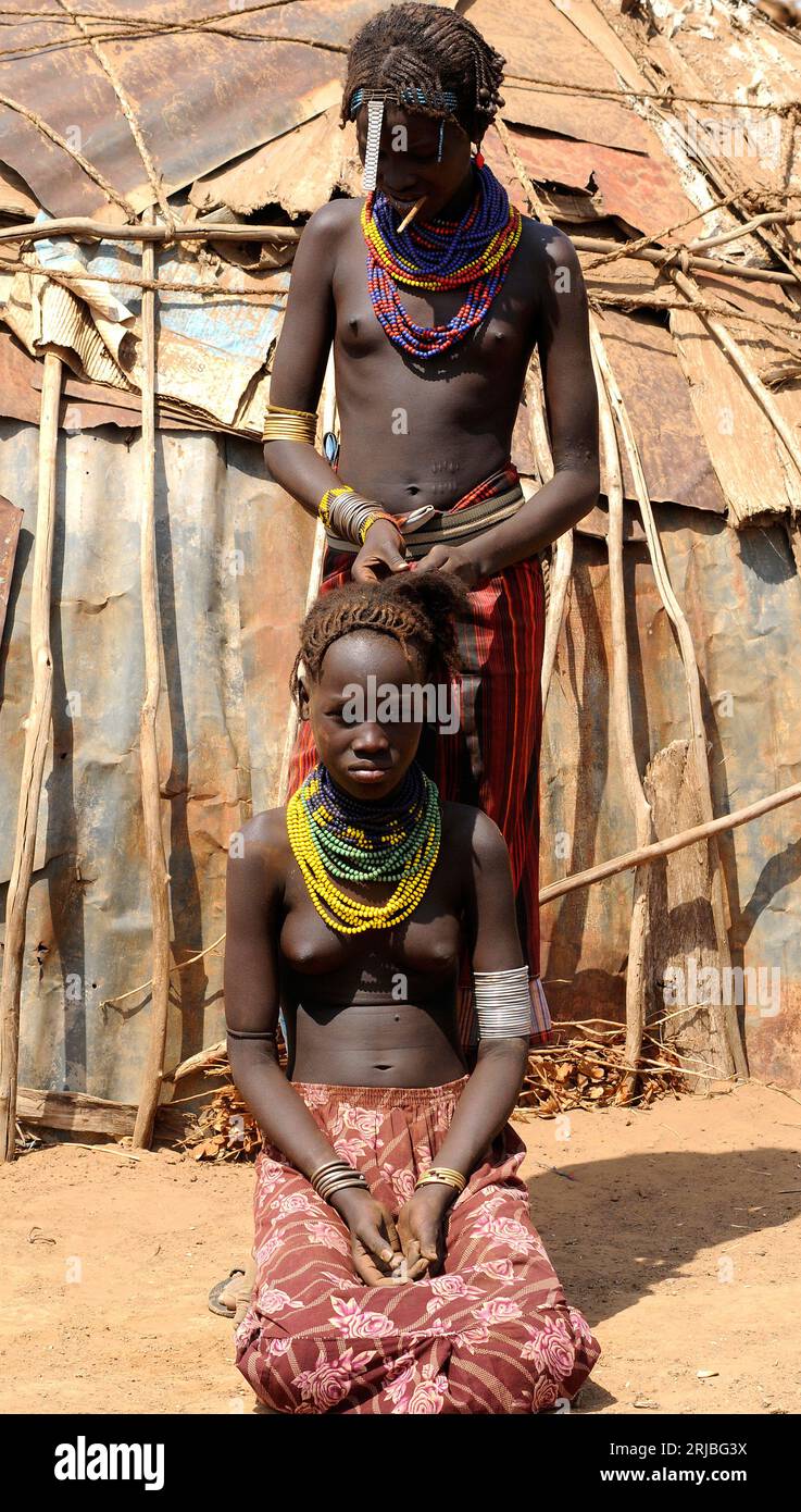 Daasanach fille peignant un ami devant sa cabane. Zone de Debub Omo, Éthiopie. Banque D'Images