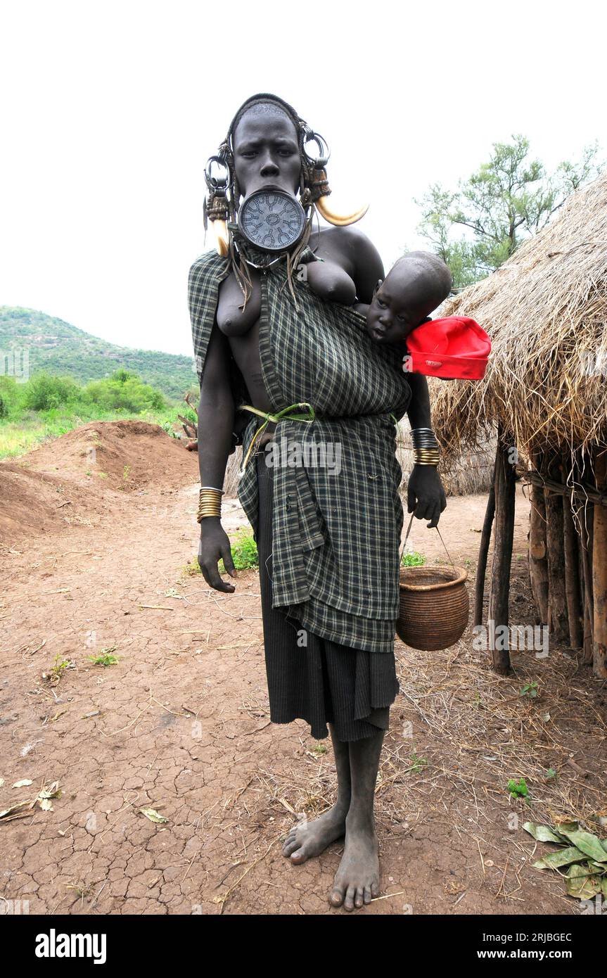 Mursi femme avec son bébé montrant sa plaque à lèvres spectaculaire. Banque D'Images