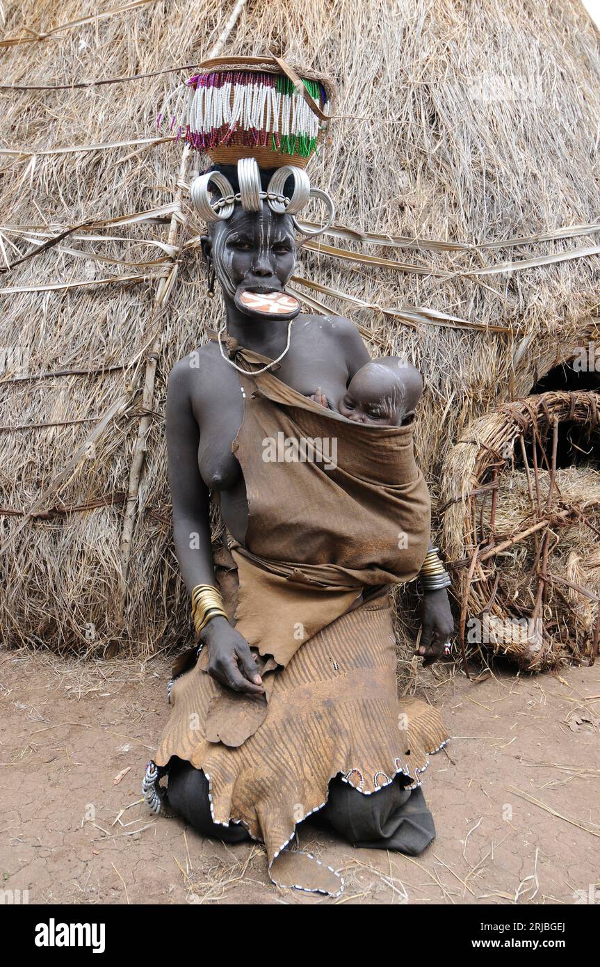 Mursi femme avec son bébé montrant sa plaque à lèvres et sa coiffure. Zone de Debub Omo, Éthiopie. Banque D'Images