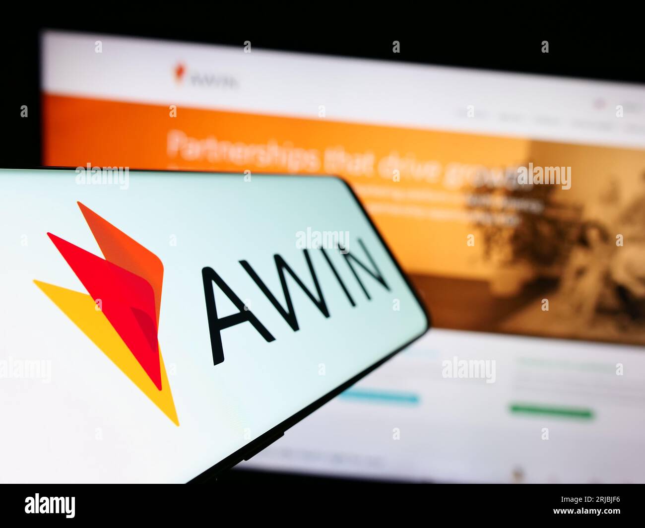 Smartphone avec logo de la société allemande de marketing en ligne AWIN AG sur l'écran devant le site Web de l'entreprise. Effectuez le focus sur la gauche de l'écran du téléphone. Banque D'Images