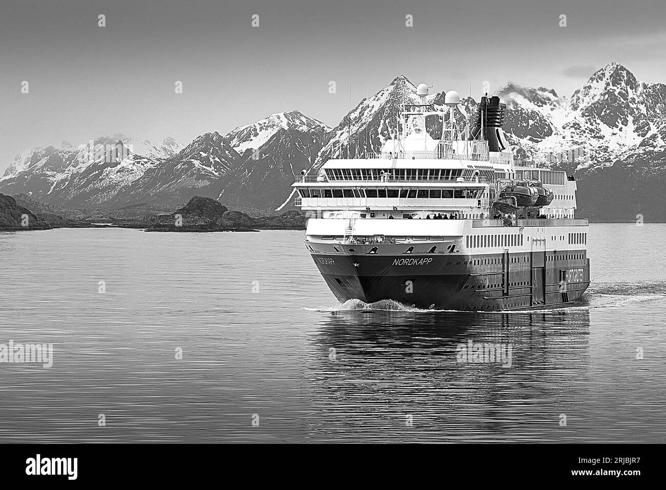 Gros plan Noir et photo du ferry norvégien Hurtigruten, MS NORDKAPP, sortant de Svolvaer, derrière les montagnes enneigées des îles Lofoten Banque D'Images