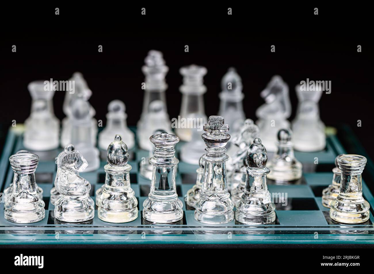 verre transparent, pièces d'échecs transparentes sur un damier, mise au point sélective, gros plan, isolé sur le noir Banque D'Images
