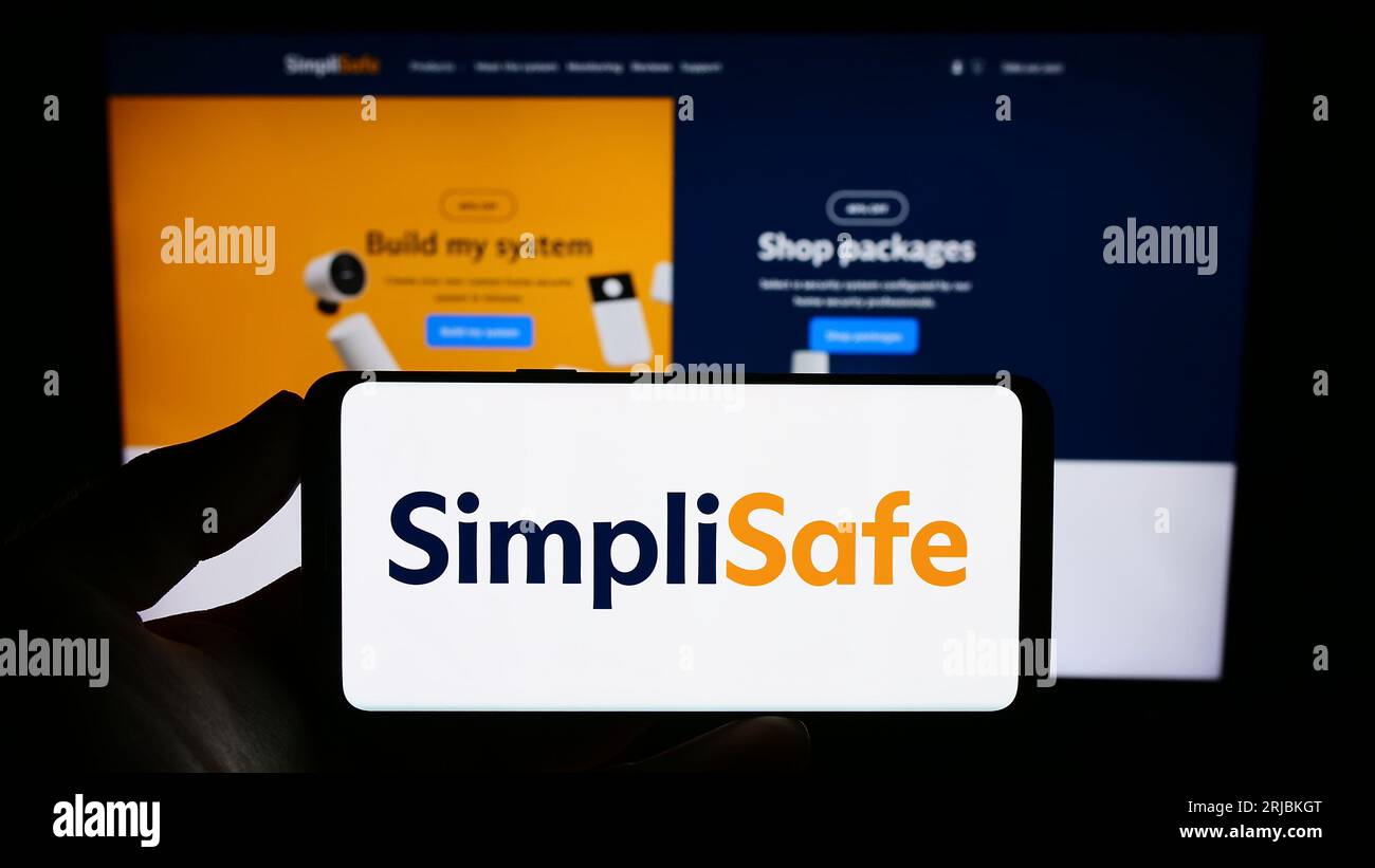 Personne tenant le smartphone avec le logo de la société de sécurité domestique américaine SimpliSafe Inc. Sur l'écran en face du site Web. Concentrez-vous sur l'affichage du téléphone. Banque D'Images