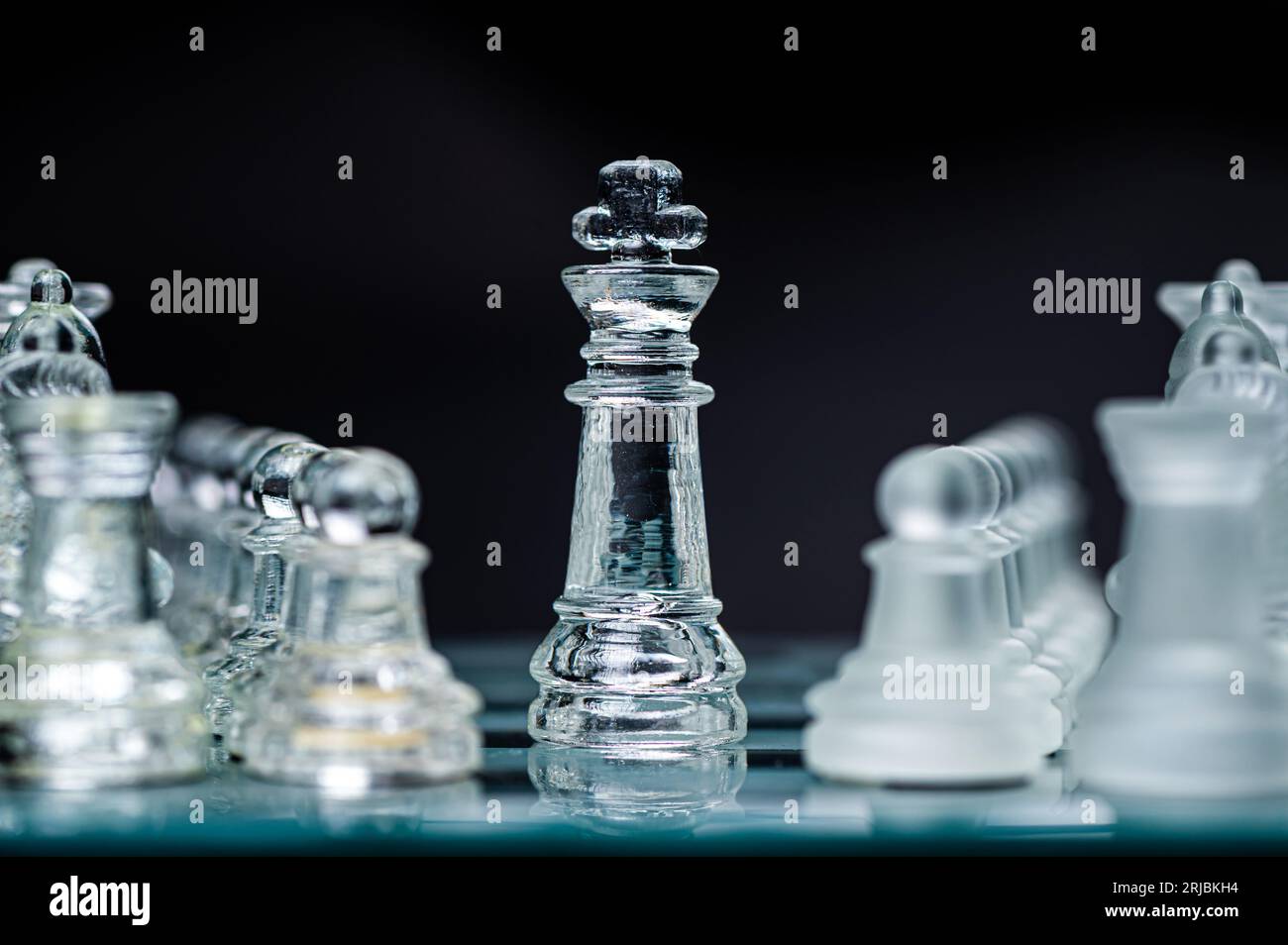 Pièces d'échecs en verre transparent sur fond sombre. Leadership, confrontation et concept de stratégie Banque D'Images
