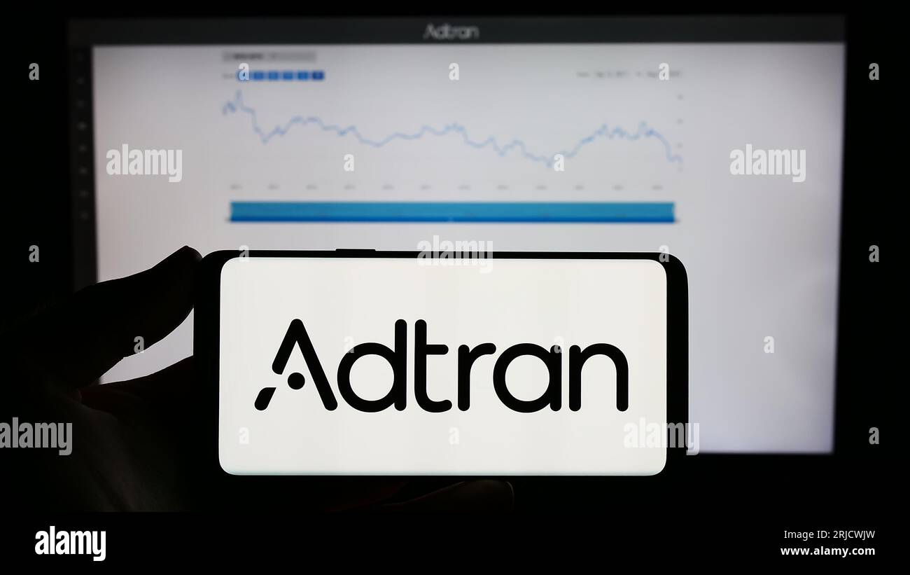 Personne détenant un téléphone mobile avec le logo de la société de télécommunications américaine Adtran Inc. Sur l'écran devant la page Web. Concentrez-vous sur l'affichage du téléphone. Banque D'Images