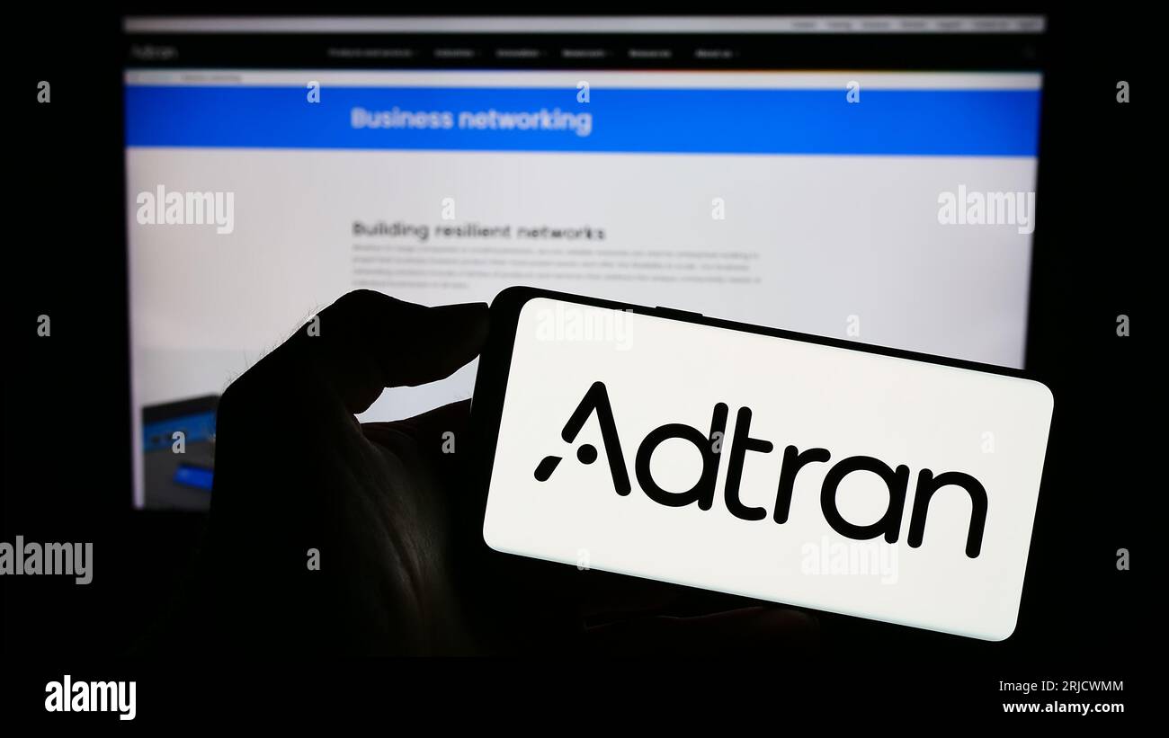 Personne détenant un téléphone cellulaire avec le logo de la société de télécommunications américaine Adtran Inc. Sur l'écran devant la page Web de l'entreprise. Concentrez-vous sur l'affichage du téléphone. Banque D'Images