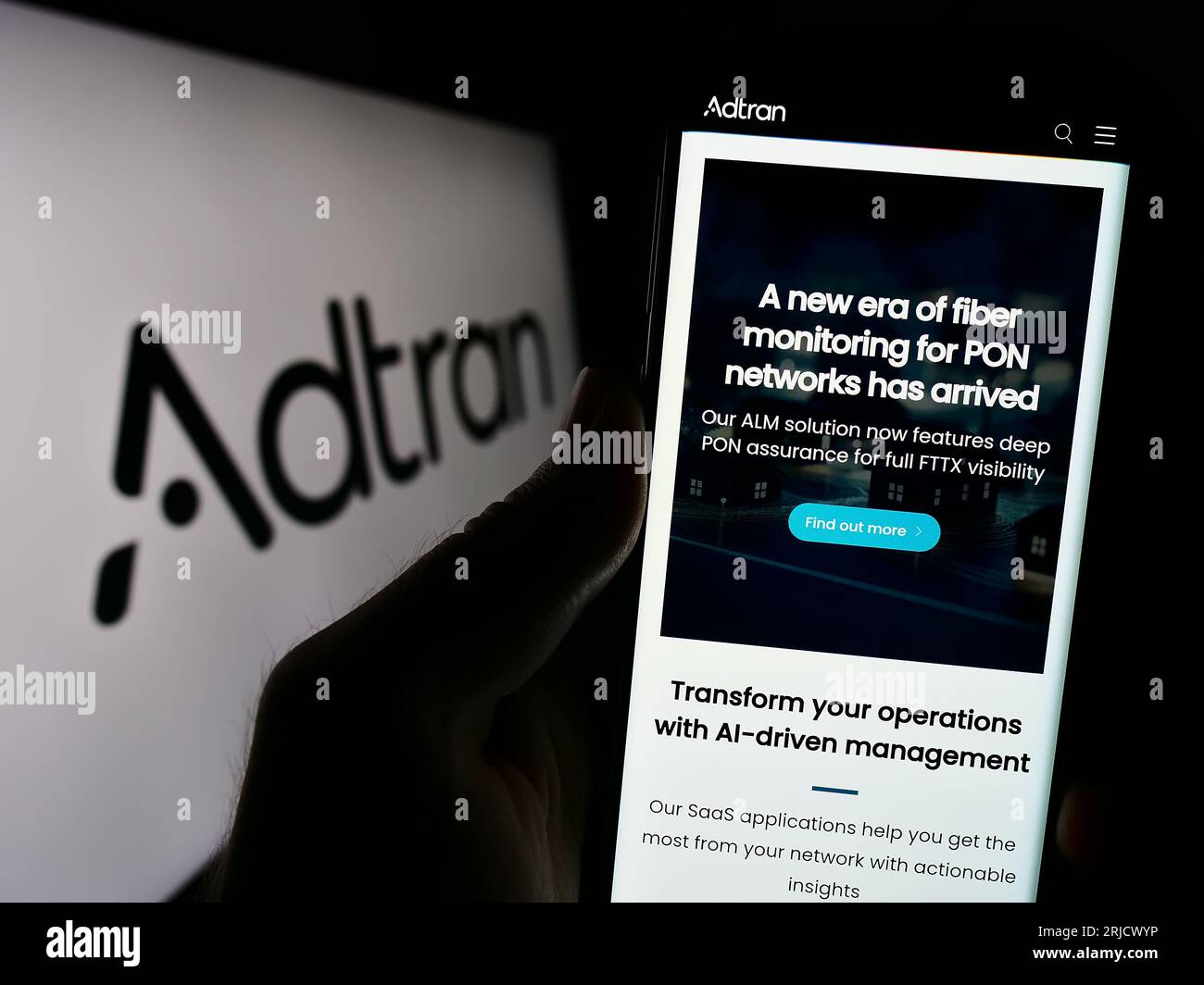 Personne tenant un téléphone cellulaire avec la page Web de la société de télécommunications américaine Adtran Inc. Sur l'écran devant le logo. Concentrez-vous sur le centre de l'écran du téléphone. Banque D'Images