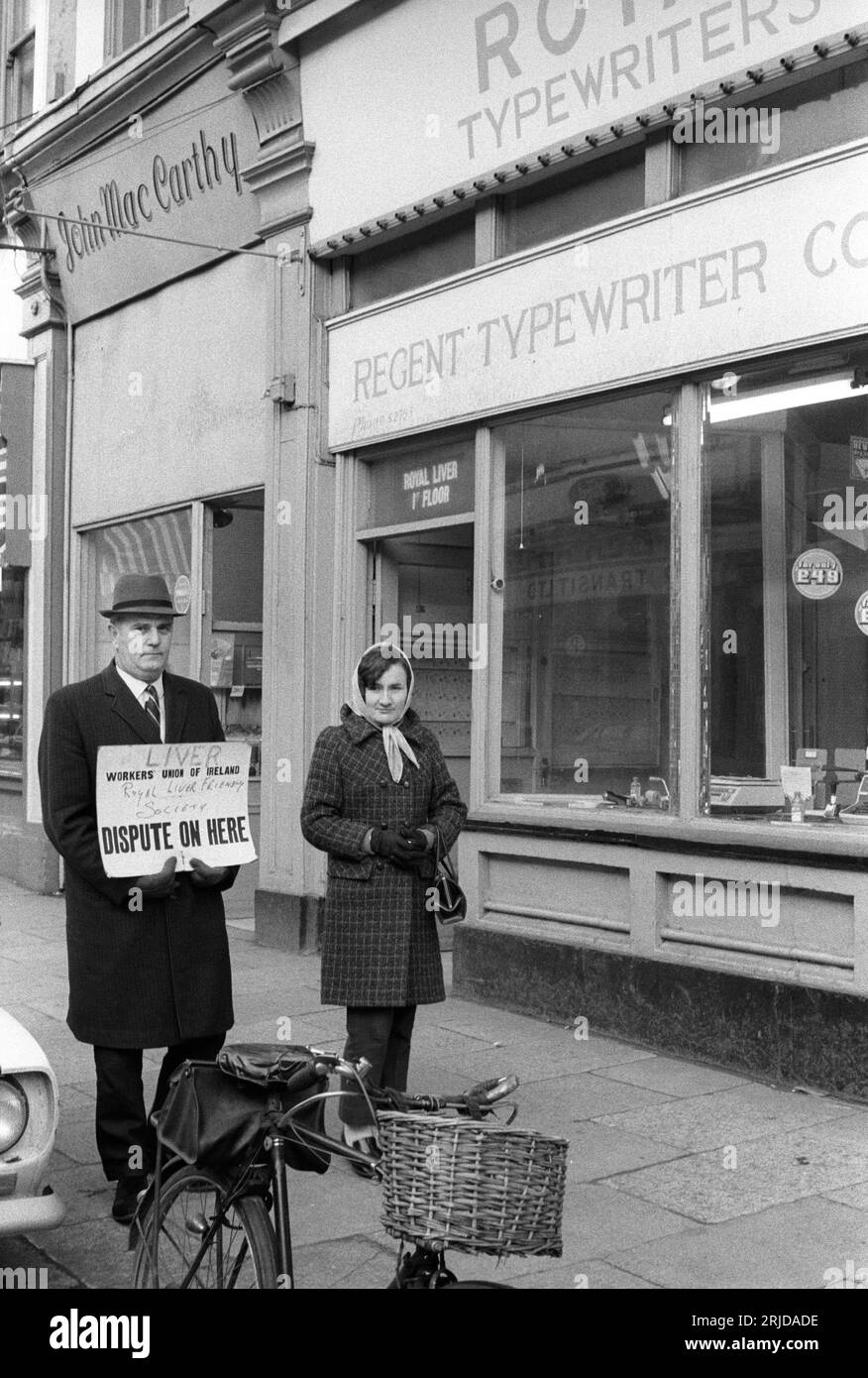 En grève, Picket Line. Deux personnes en grève devant leur bureau qui se trouve au premier étage au-dessus de l'atelier de machines à écrire. La pancarte dit "FOIE, la Royal Liver friendly Society. Workers Union of Ireland, DISPUTE ICI." Killorglin, Eire, Irlande du Sud vers 1972. HOMER SYKES Banque D'Images