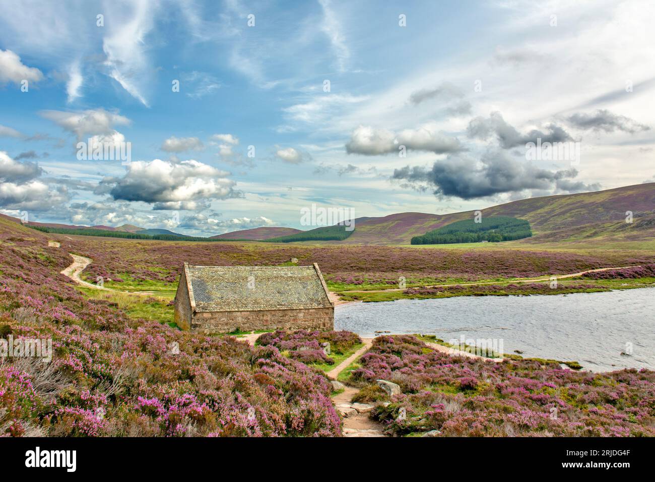 Loch Muick Ballater Balmoral Estate Scotland le hangar à bateaux en pierre et un ciel bleu sur la bruyère violette en été Banque D'Images