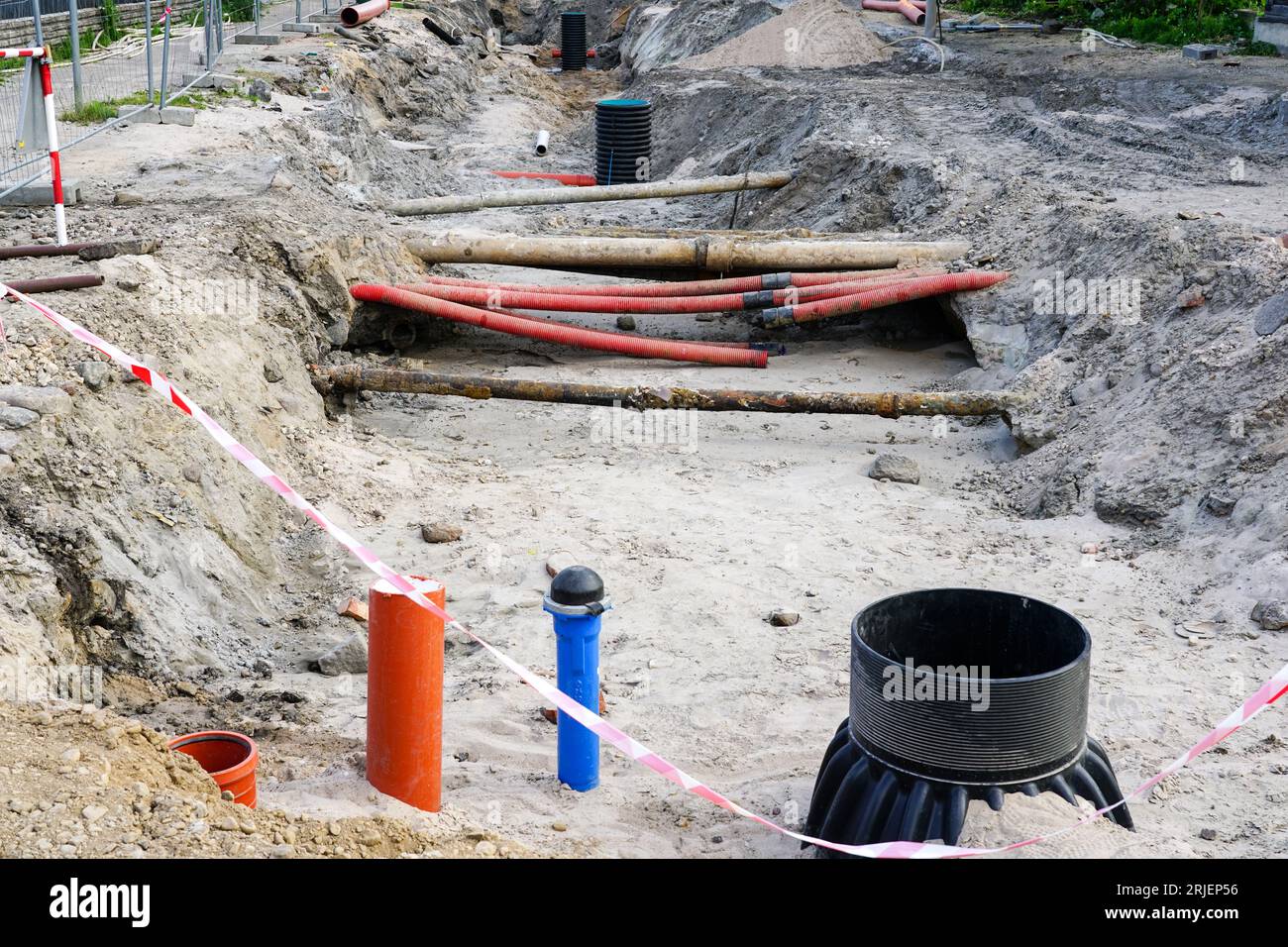 Vue de reconstruction de rue avec tranchée profonde, tuyaux souterrains anciens et remplacés, nouveau puits en plastique vertical Banque D'Images