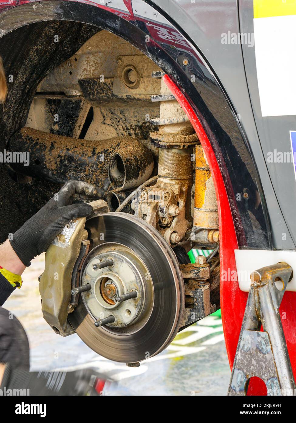 Entretien de la voiture de rallye dans le parc de service, roue déposée, disque de frein avec étrier, suspension boueuse Banque D'Images
